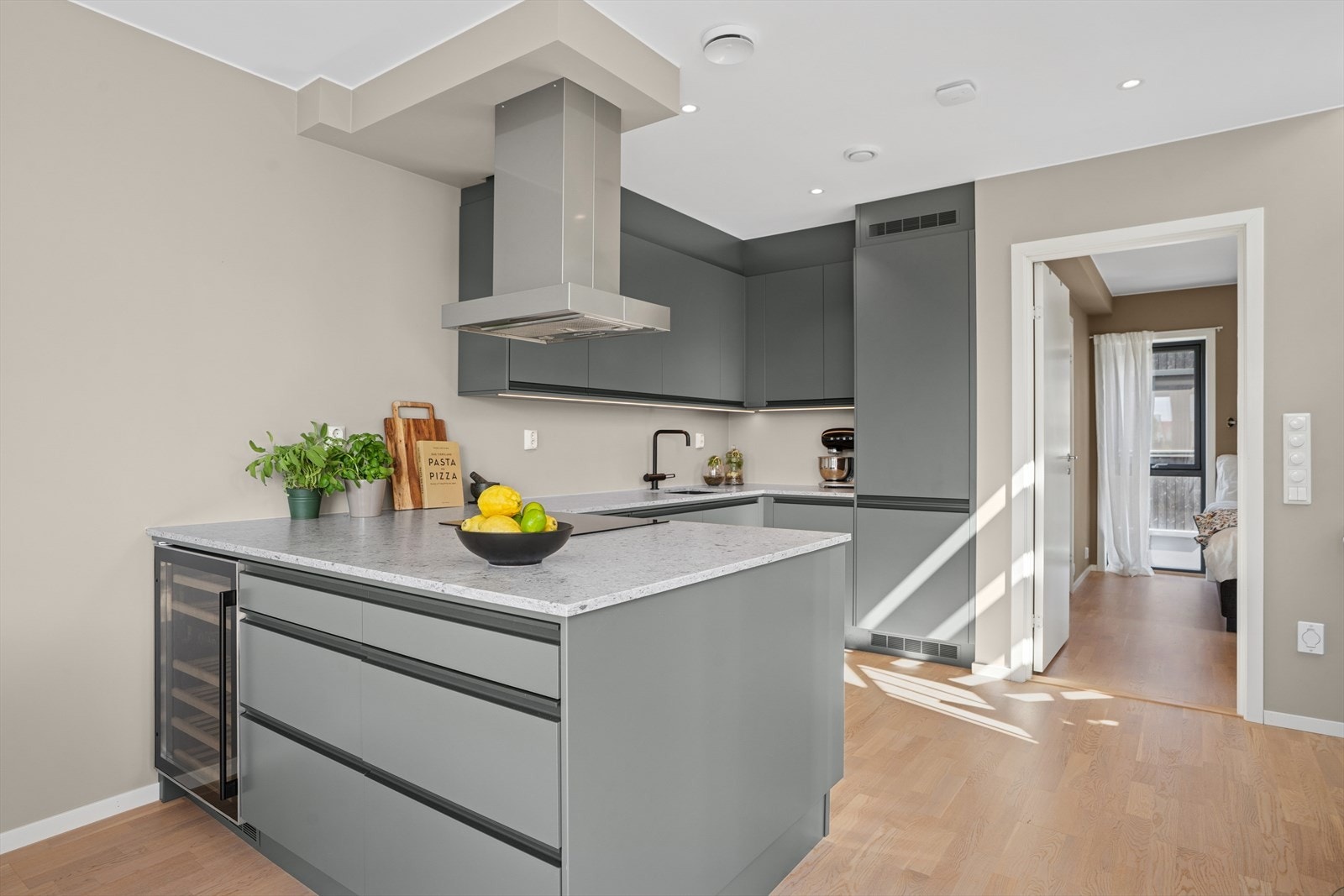 Påkostet kjøkkeninnredning med integrerte hvitevarer og forlengelse av øy med vinskap. Galleribilde