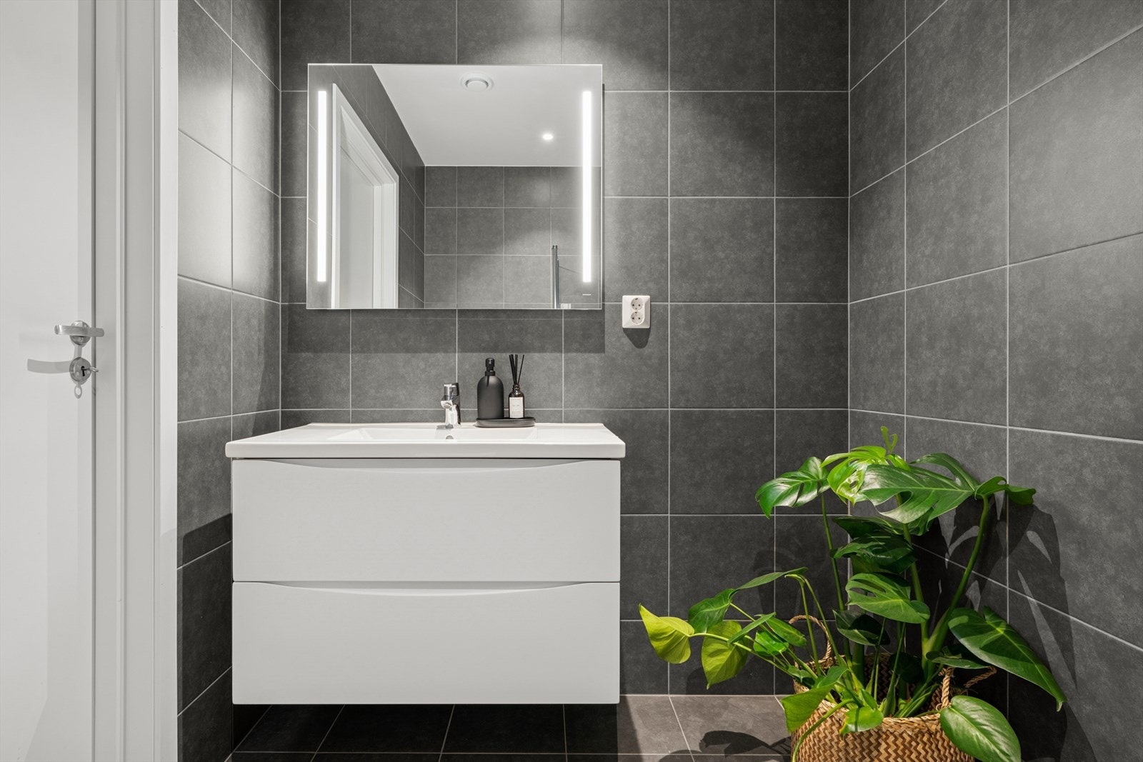 Badet er innredet med nedfelt servant, veggmontert toalett og nedsenket dusjhjørne med dører i herdet glass. Galleribilde