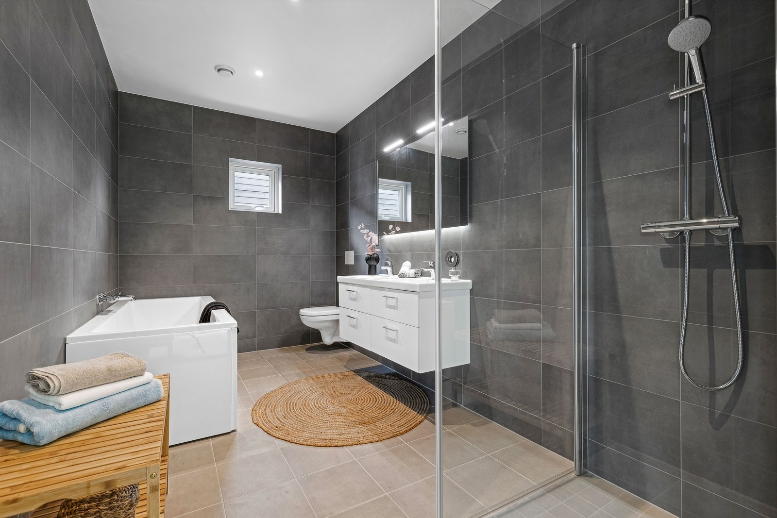 Badet i 2.etasje er av samme pene utførelse som bad 1, med tidløse fliser og behagelig gulvvarme. Her er det både dusjnise, badekar, toalett og dobbel servantinnredning med integrert belysning. Galleribilde