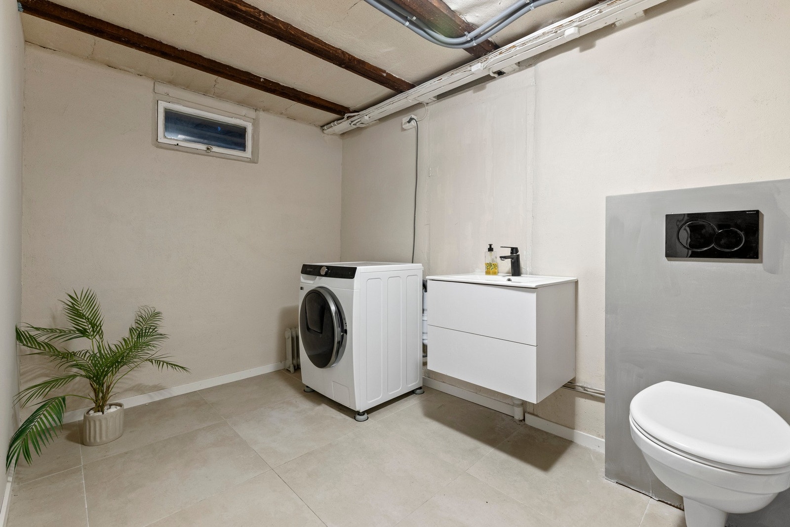 Vaskerommet har servant med slette fronter, veggmontert toalett og opplegg for vaskemaskin Galleribilde