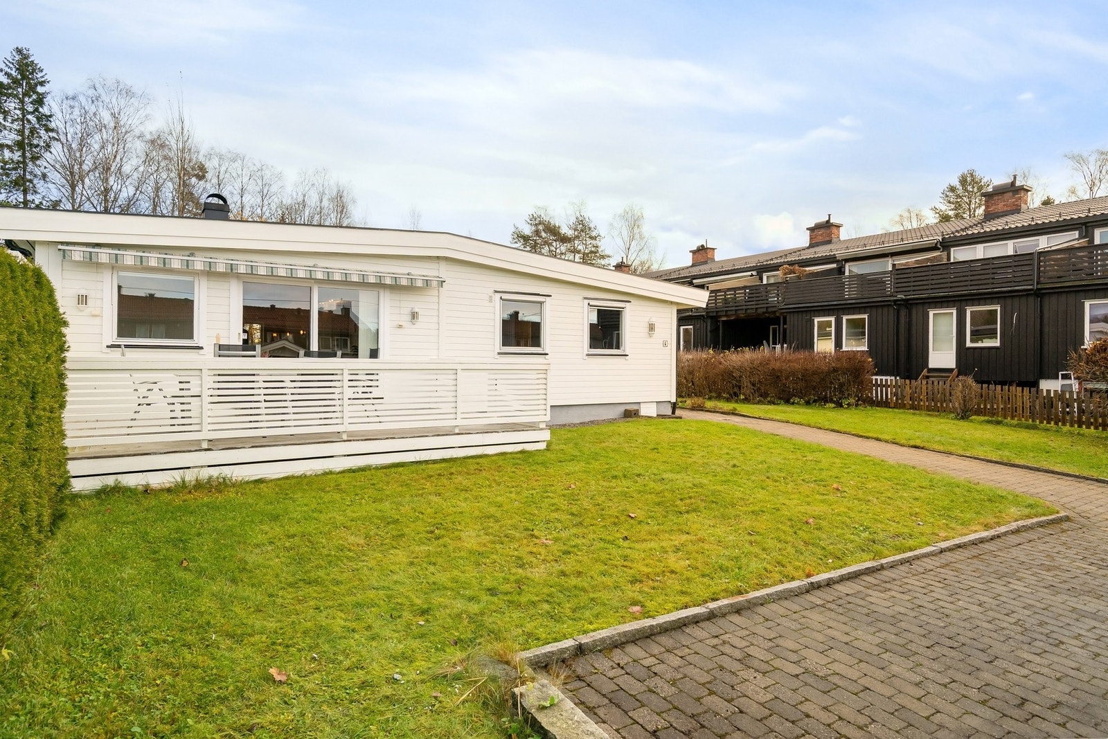 Store deler av tomten har hage, men er også pent steinlagt fra garasje til inngangsparti Galleribilde