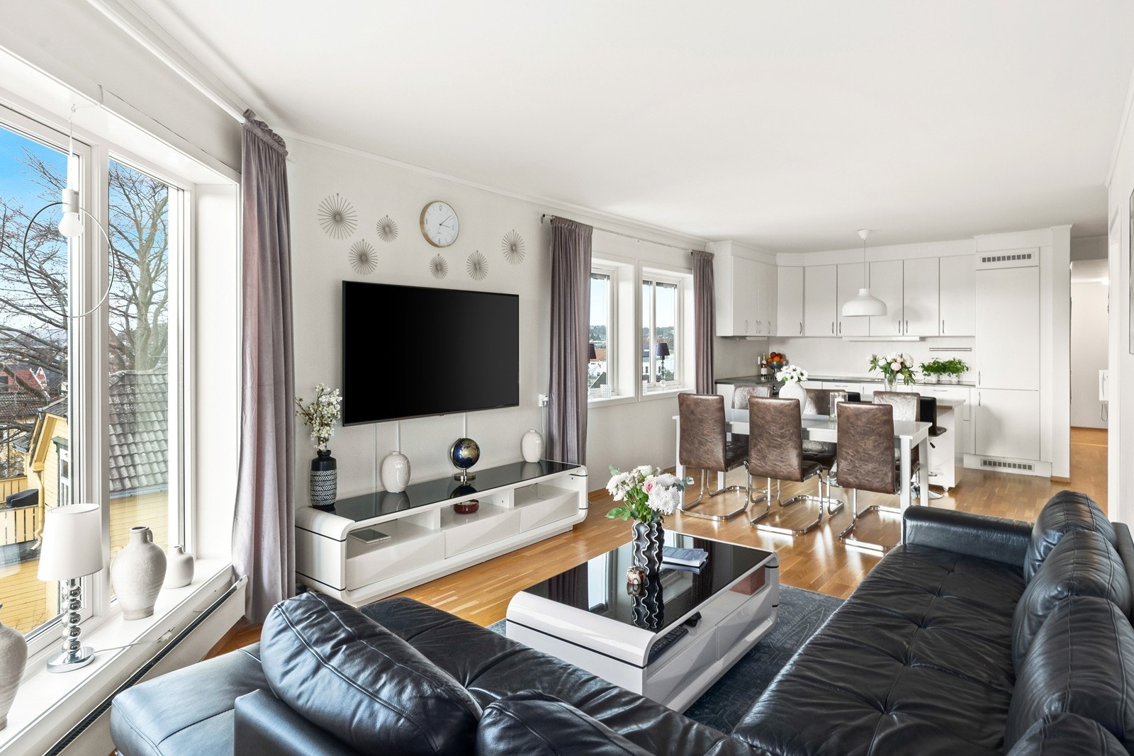 Stuen har god plass til både sofagruppe og spisebord, og den praktiske kjøkkenøya skiller elegant mellom de to sonene. Galleribilde