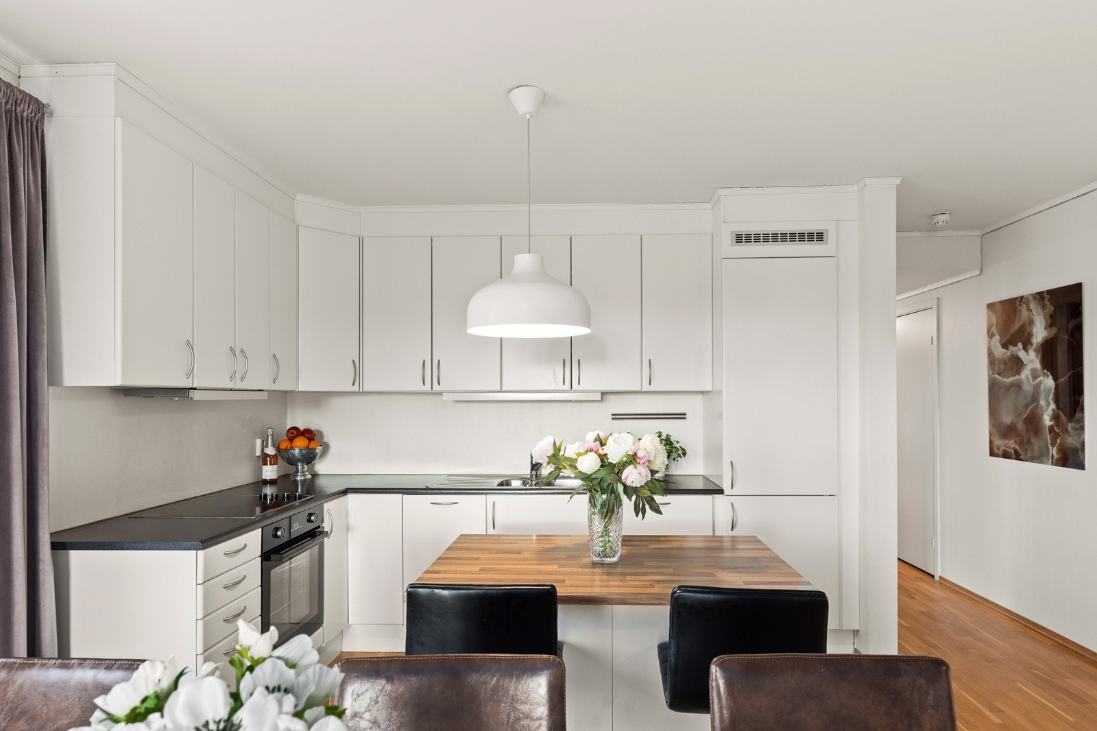 Kjøkkenet har et rent design med slette fronter og en praktisk laminat benkeplate. Det er fullt utstyrt med integrert komfyr, platetopp, kjøl/fryseskap, og oppvaskmaskin, som forener klassisk stil med moderne funksjonalitet. Galleribilde