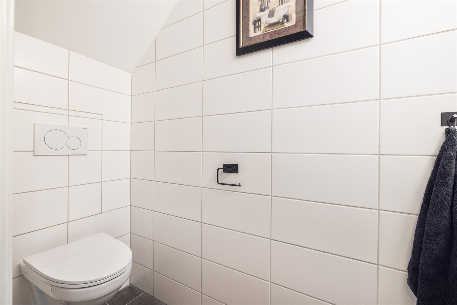 Gjestetoalett med adkomst fra gangen er helfliset og utstyrt med vegghengt toalett og servant med skuffer under. Galleribilde