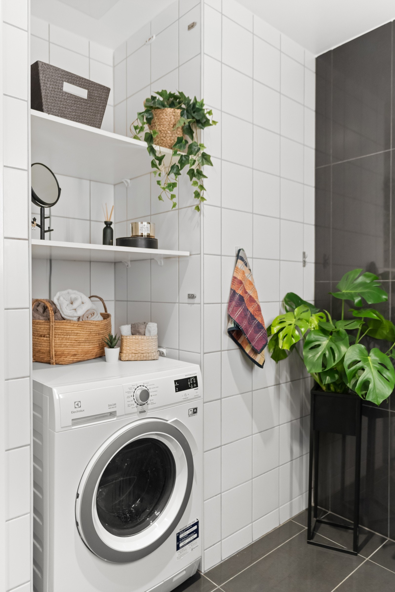 Vaskemaskinen er plassert i en praktisk nisje med flere hyller til oppbevaring. Galleribilde