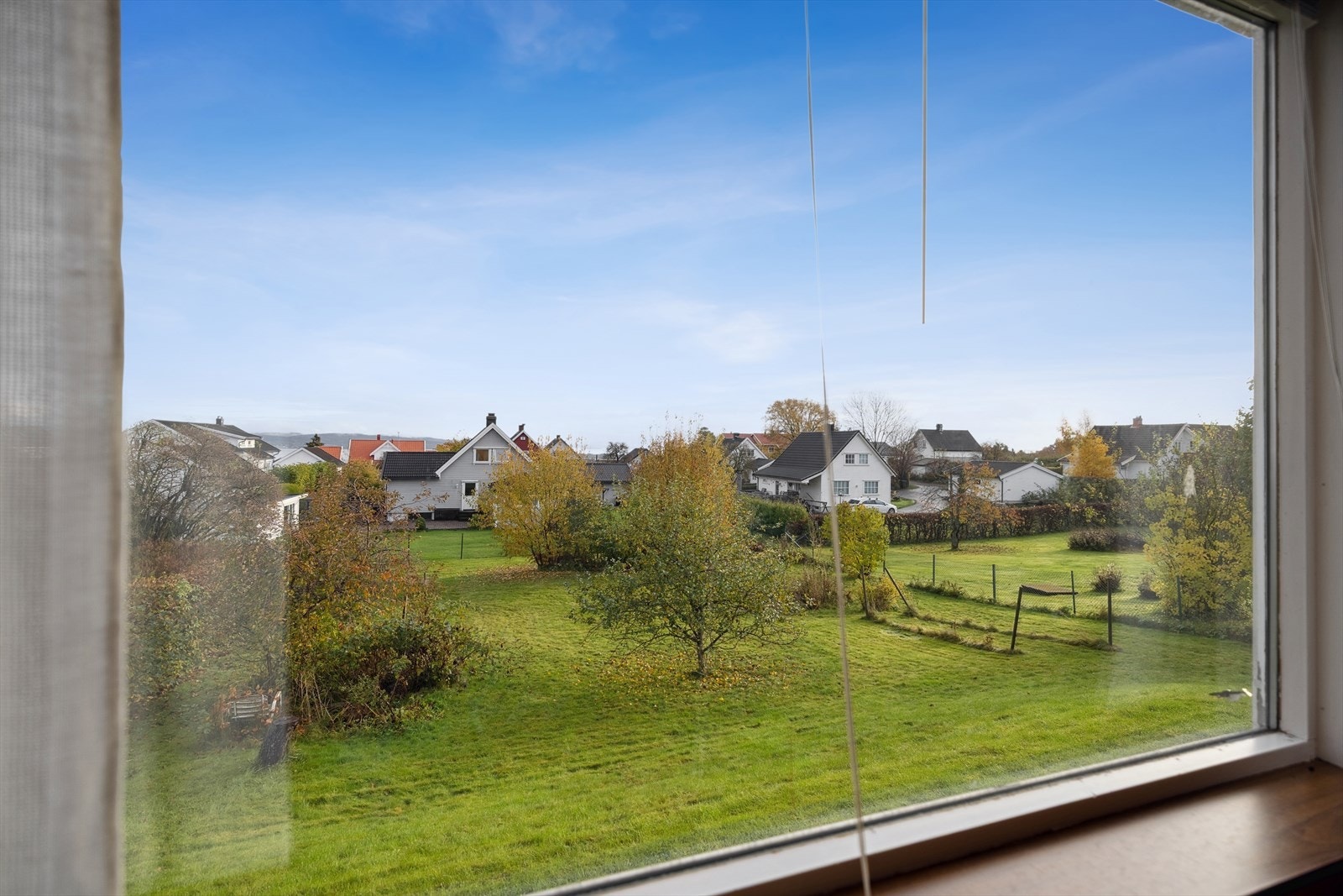 Store vinduer gir utsikt mot et frodig hageområde. Galleribilde