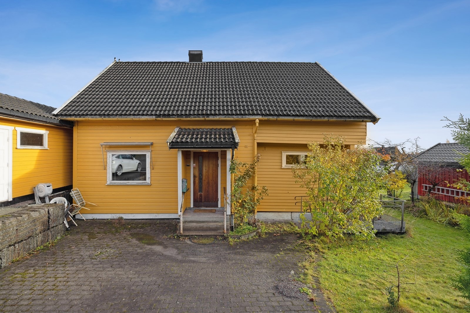 Inngangsdøren er av teak fra 1983, med værslitte karmer og behov for vedlikehold. Galleribilde