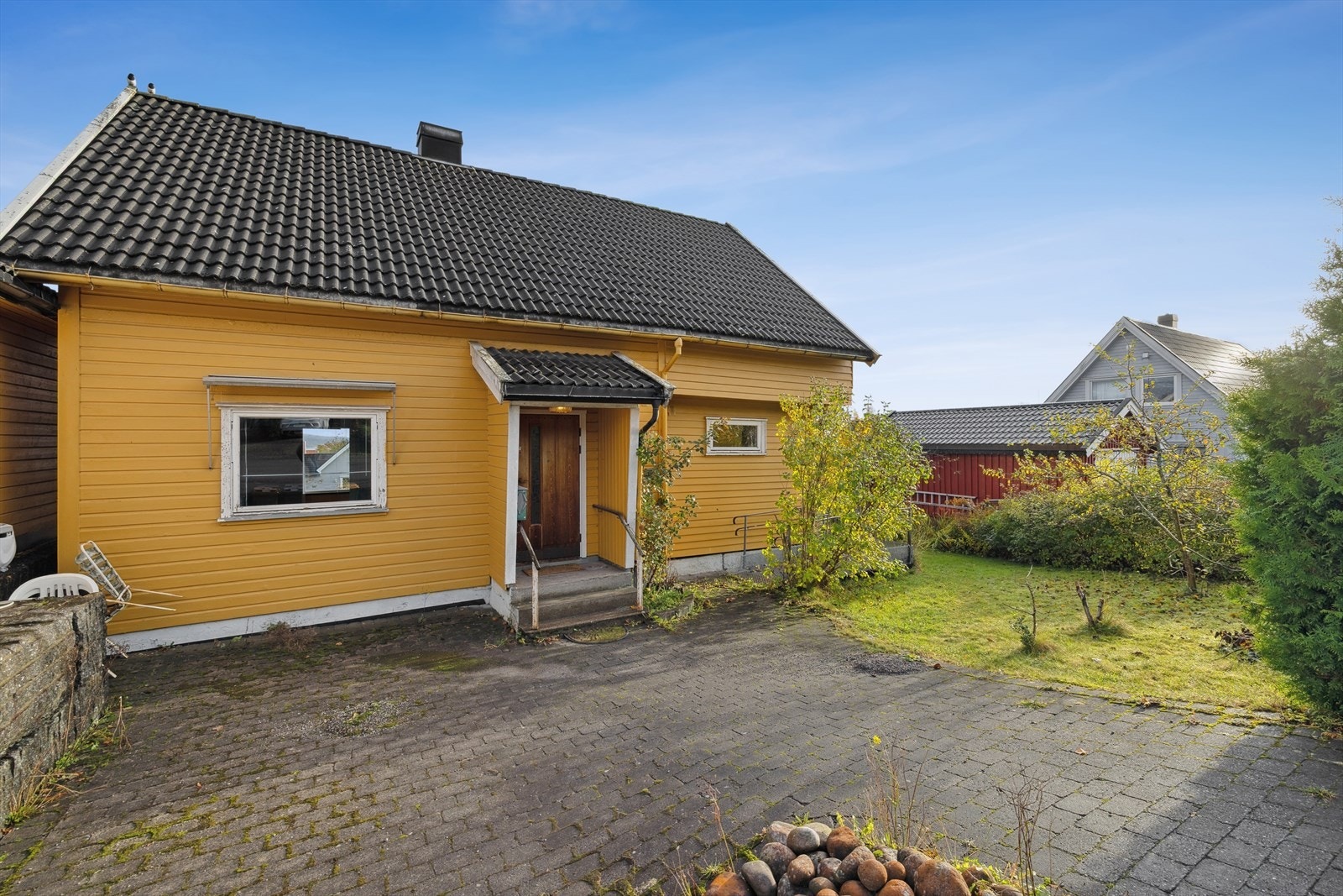 Belegningsstein på gårdsplass heller nedover, med behov for terrengjustering for å sikre tilstrekkelig fall fra muren. Galleribilde