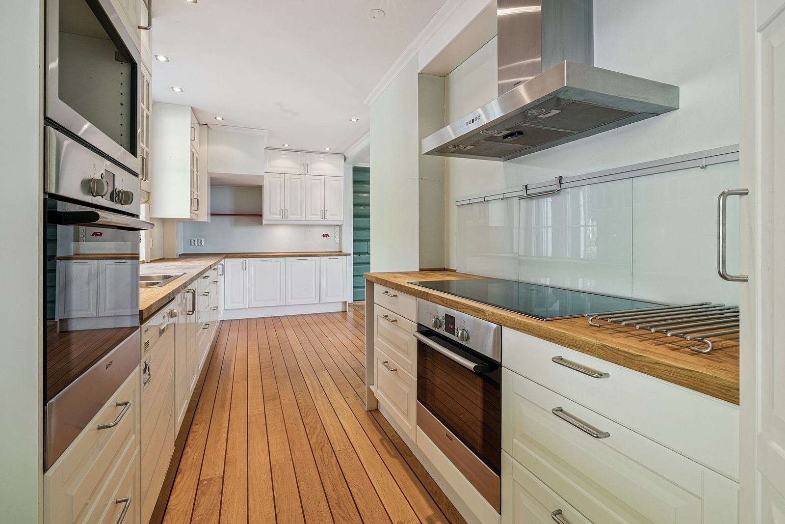 Kjøkken med oppvaskmaskin, kjøleskap og komfyr med koketopp. Galleribilde