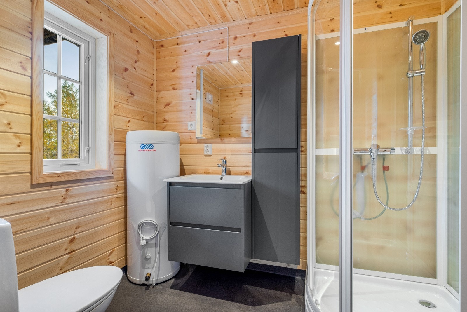 Badet ligger innenfor gangen i 1.etasje. Rommet er innredet med toalett, dusjkabinett, speil, servant med servantskap og høyskap. Galleribilde