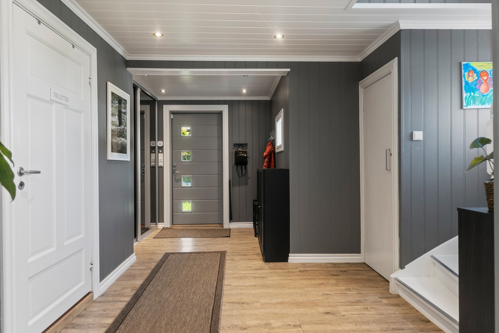 Fra det overbygde inngangspartiet kommer du inn i en romslig entré med god garderobeplass bak skyvedører med speil Galleribilde