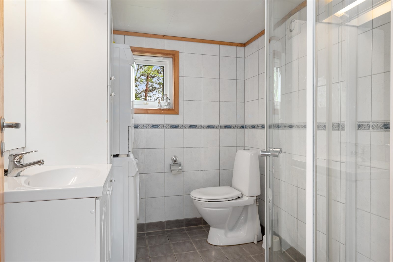 Badet er opplyst renovert ca. 2008. Rommet har flislagt gulv med behagelig gulvvarme og er innredet med servantskap, høyskap, opplegg for vaskemaskin, toalett og dusjhjørne med svingdører. Galleribilde