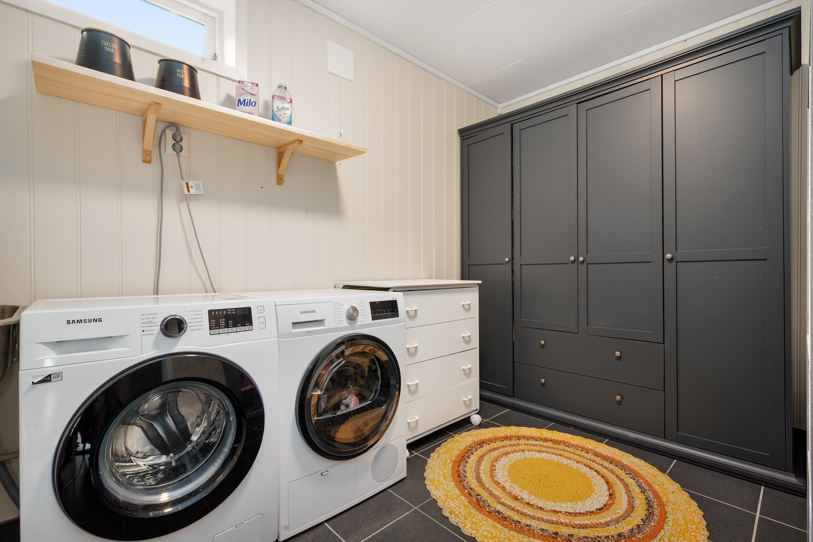 Vaskerommet har flislagt gulv med gulvvarme og er innredet med vaskekum, opplegg for vaskemaskin og stort garderobeskap med god oppbevaringsplass. Galleribilde