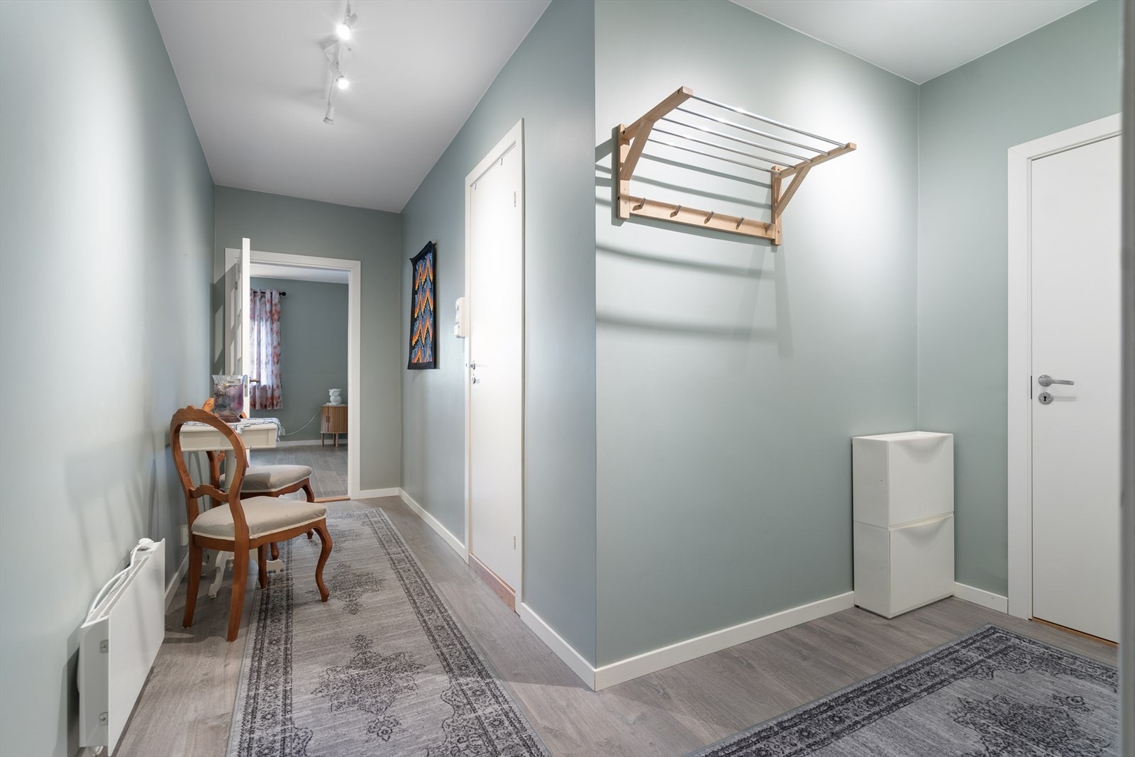 Lys gang med behagelige fargetoner og plass til både oppbevaring og en liten sittegruppe Galleribilde