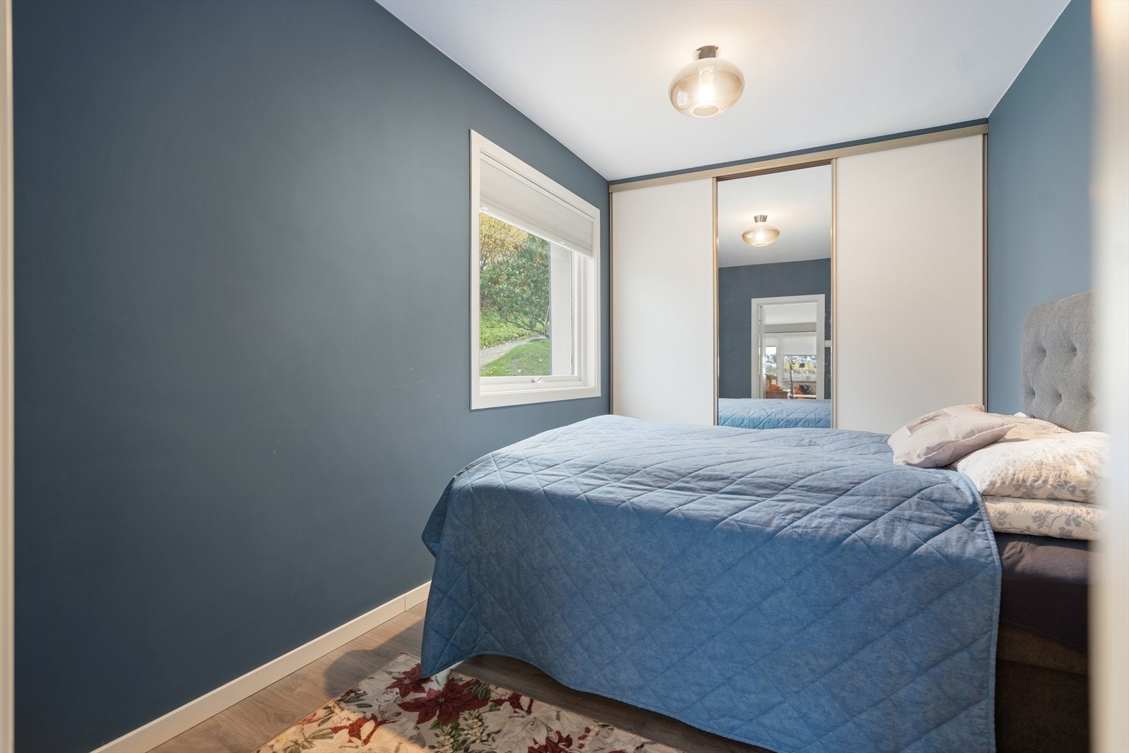 Soverom 1 - Rolig atmosfære med lune blåtoner og naturlig lys fra vinduet gir et avslappende uttrykk Galleribilde