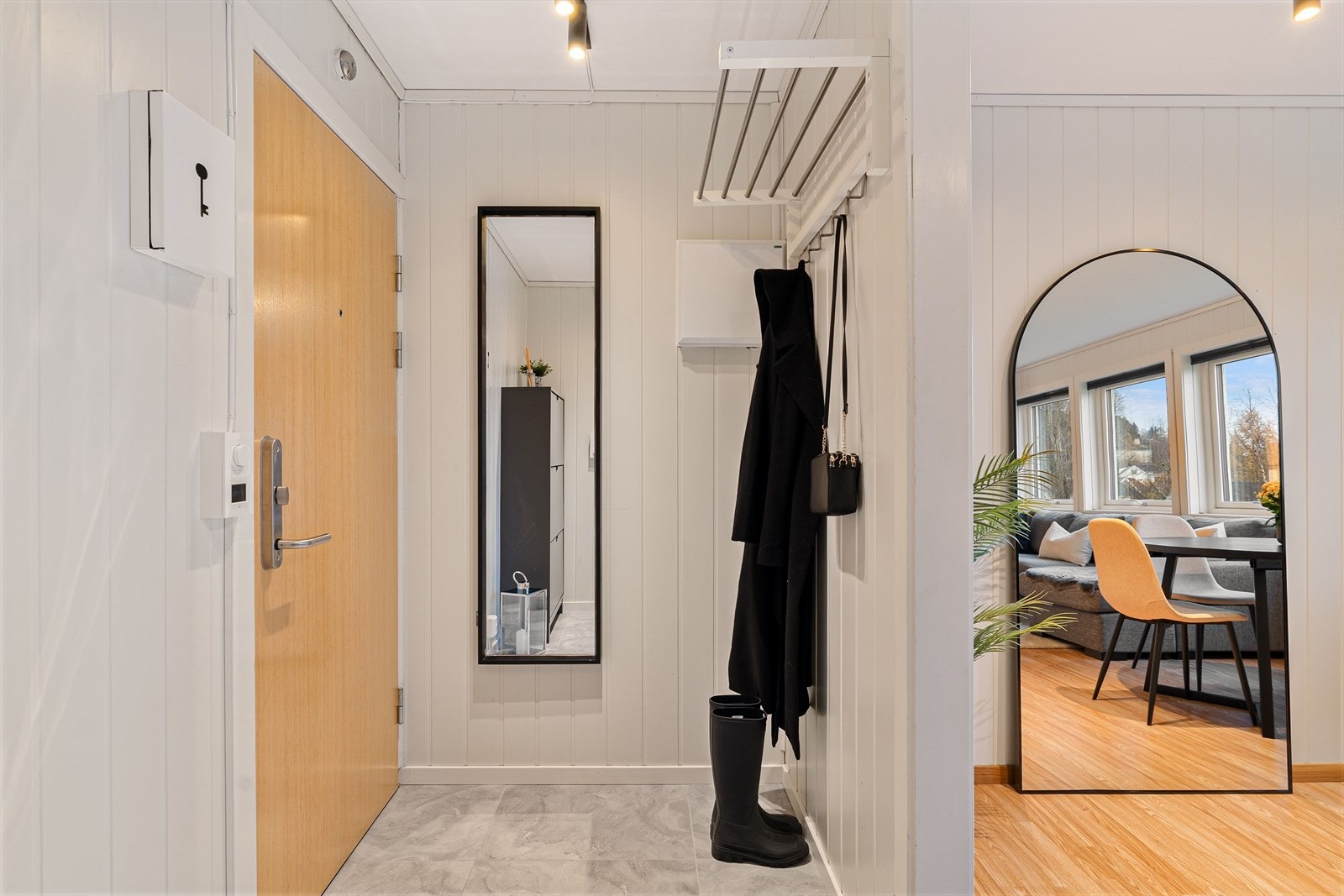 Man går opp til 1. etasje og kommer inn i en entré/gang på 3,5 kvm, som gir muligheter for oppbevaring av yttertøy og sko. Man blir møtt med flis på gulv med behagelig gulvvarme, samt sort spotskinne i tak. Galleribilde