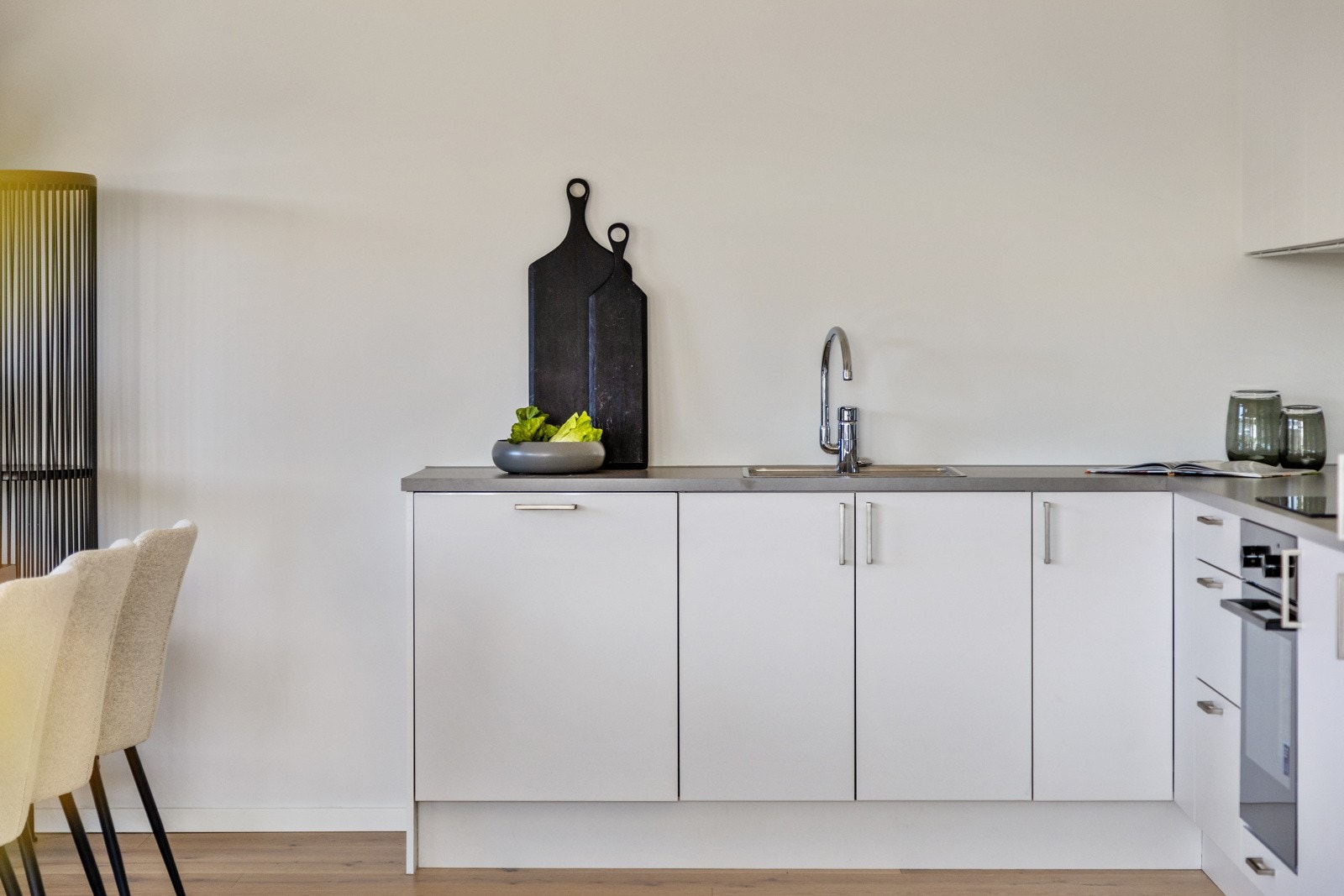 Moderne kjøkken med hvite skap, grå benkeplate og integrerte hvitevarer. Galleribilde