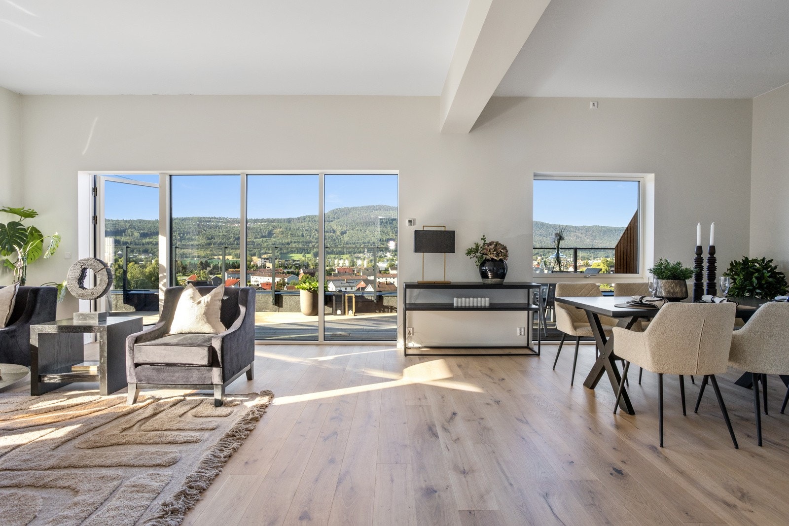 Lys og romslig stue med store vindusflater og utsikt mot grønne åser og nærområdet. Galleribilde