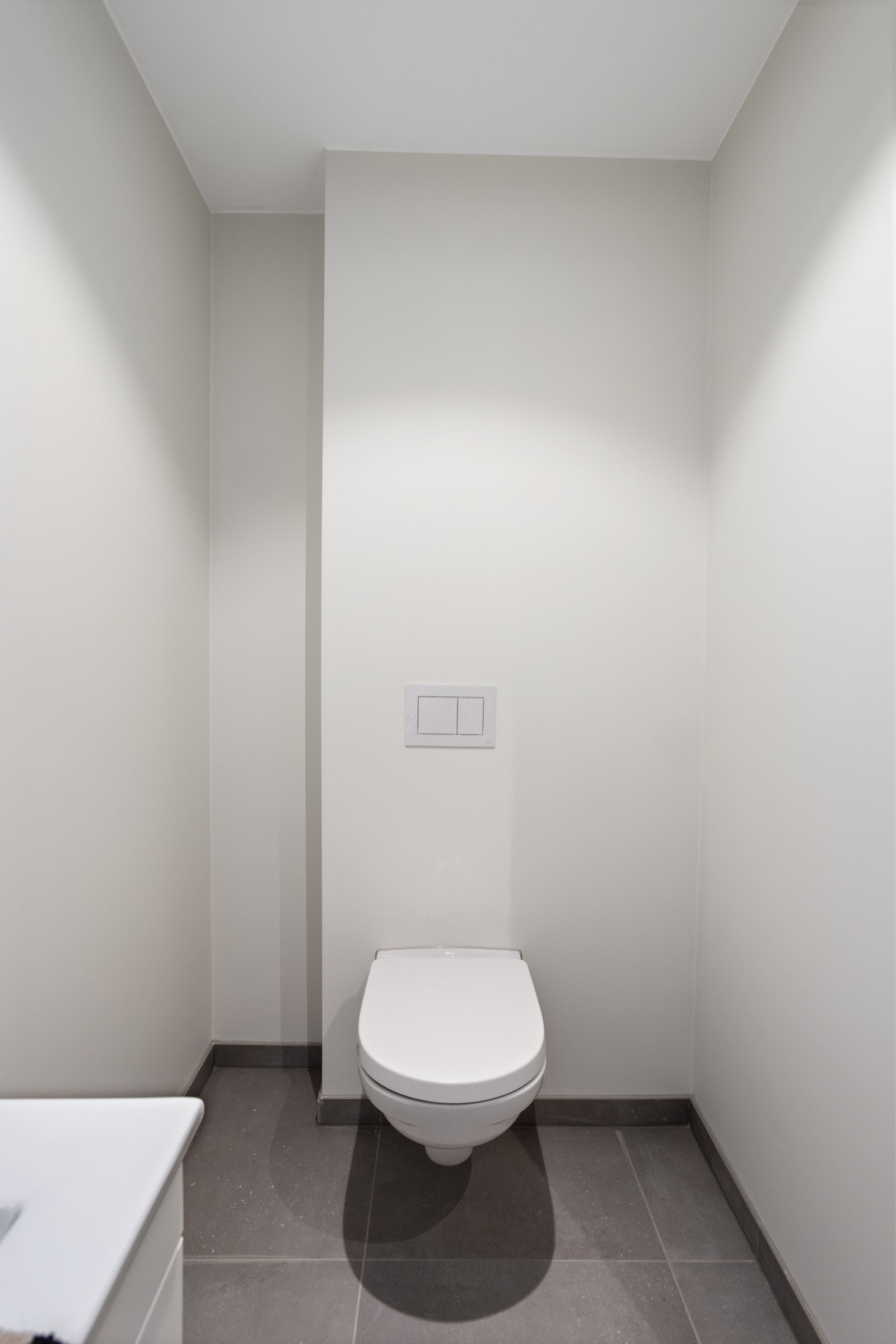 Toalettrom med vegghengt toalett og flislagt gulv. Galleribilde