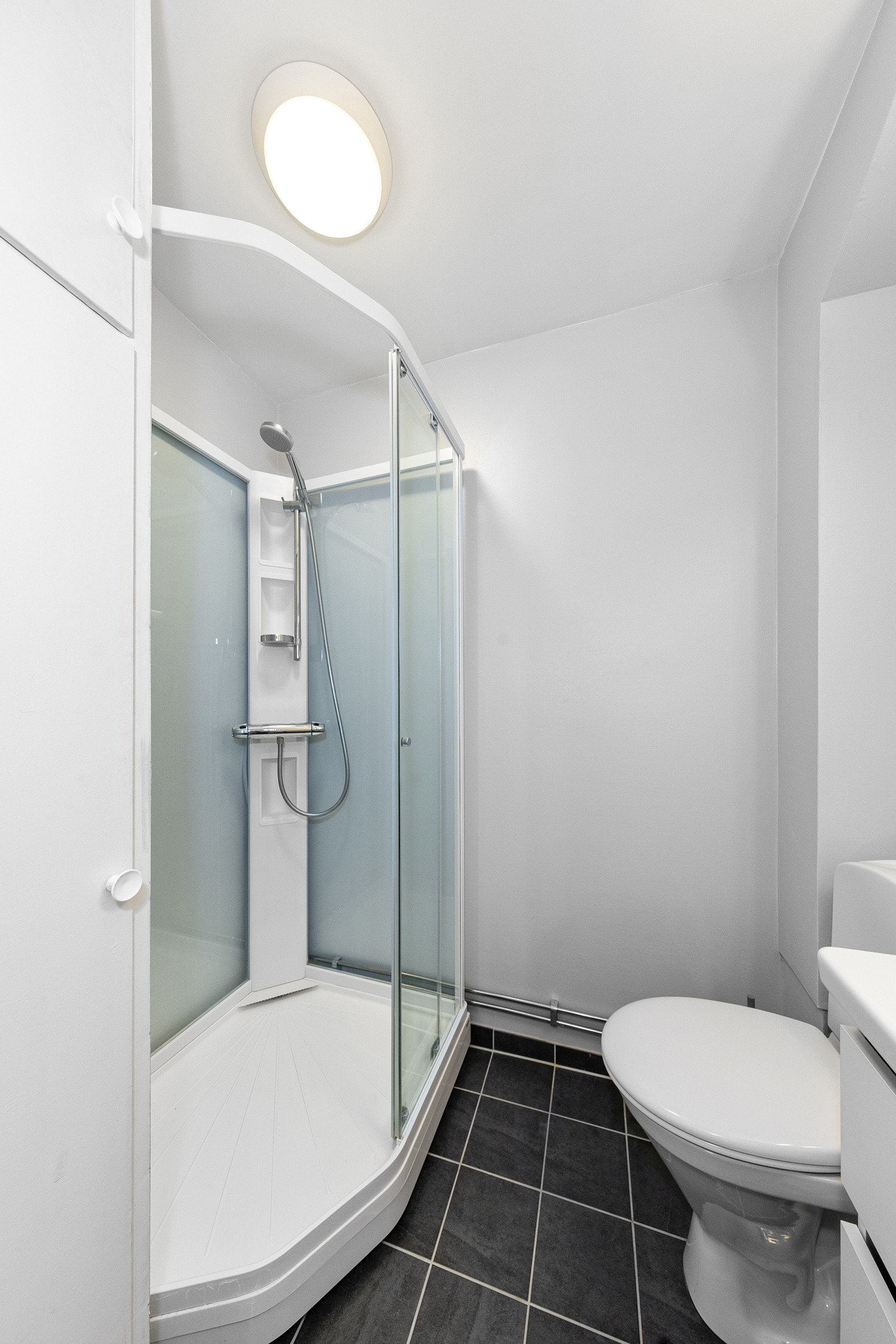 Badet har dusjkabinett, servant i innredning m/skuffer, toalett og plassbygd høyskap Galleribilde