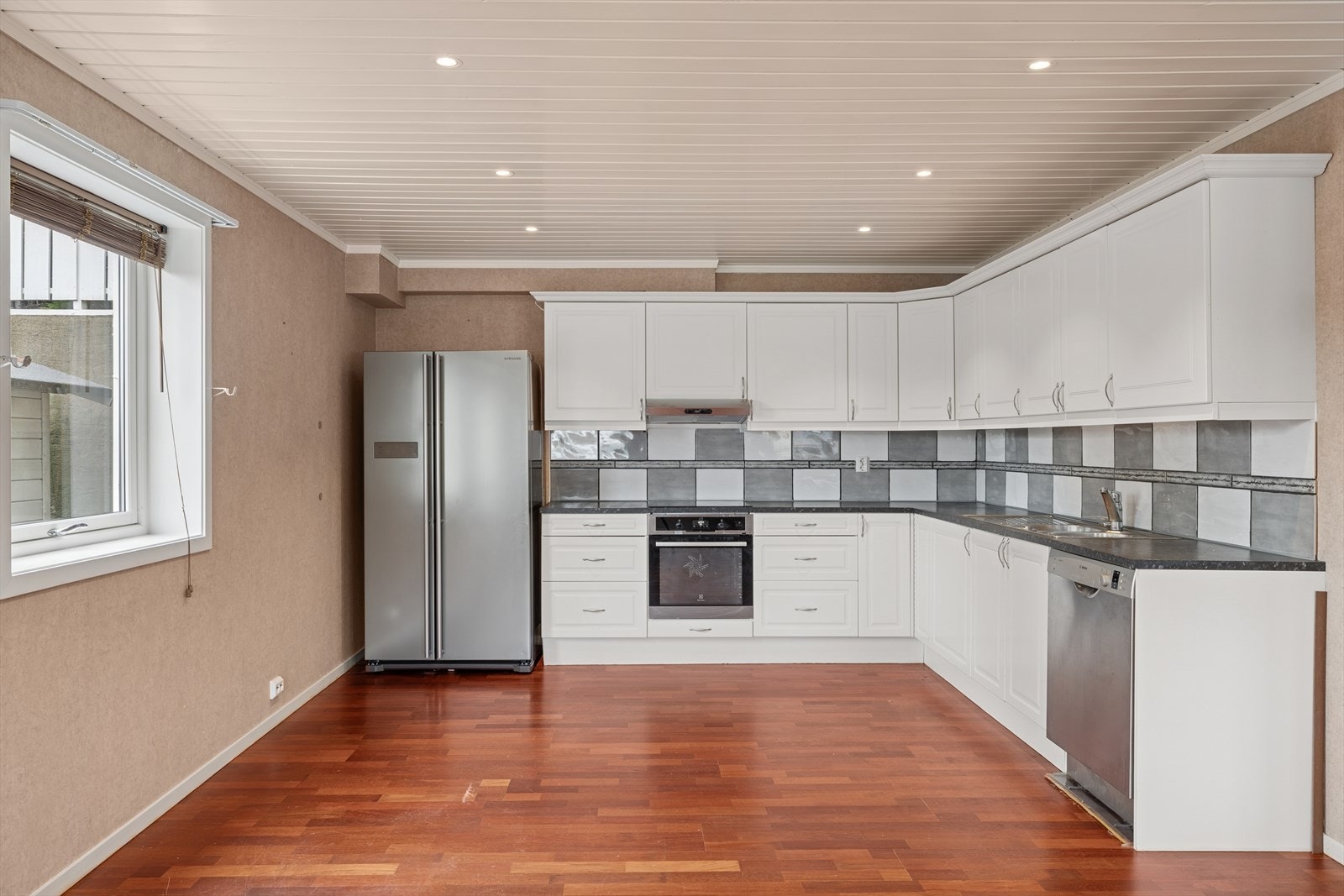 Stuen står i en åpen løsning mot kjøkkenet. Kjøkkenet er innredet med profilerte fronter og laminat benkeplate med nedfelt vaskekum. Galleribilde