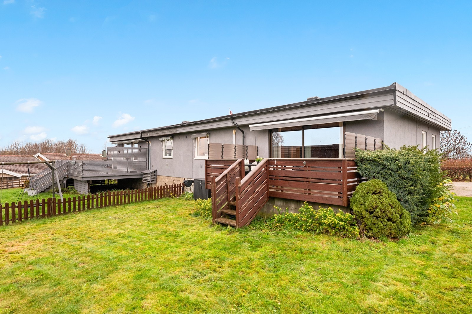 Grønn og åpen tomt med busker og plen, samt felles gruset adkomstvei med nabo. Galleribilde