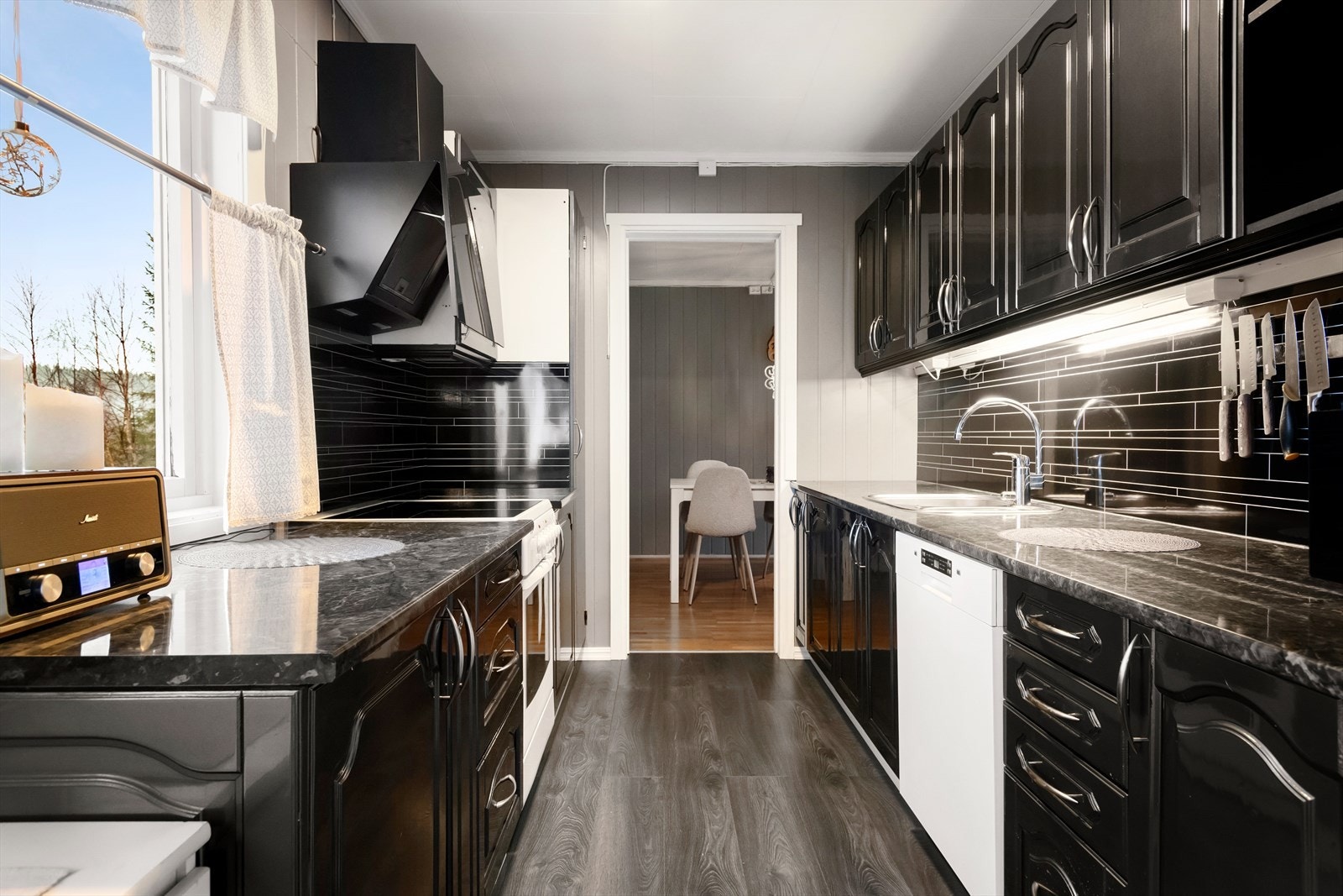 Kjøkkeninnredningen har fått opplakkert skapdørene i sort høyglans og det er plass til kjøkkenmøblement der utgangsdøra til altan mot nord er plassert. Galleribilde