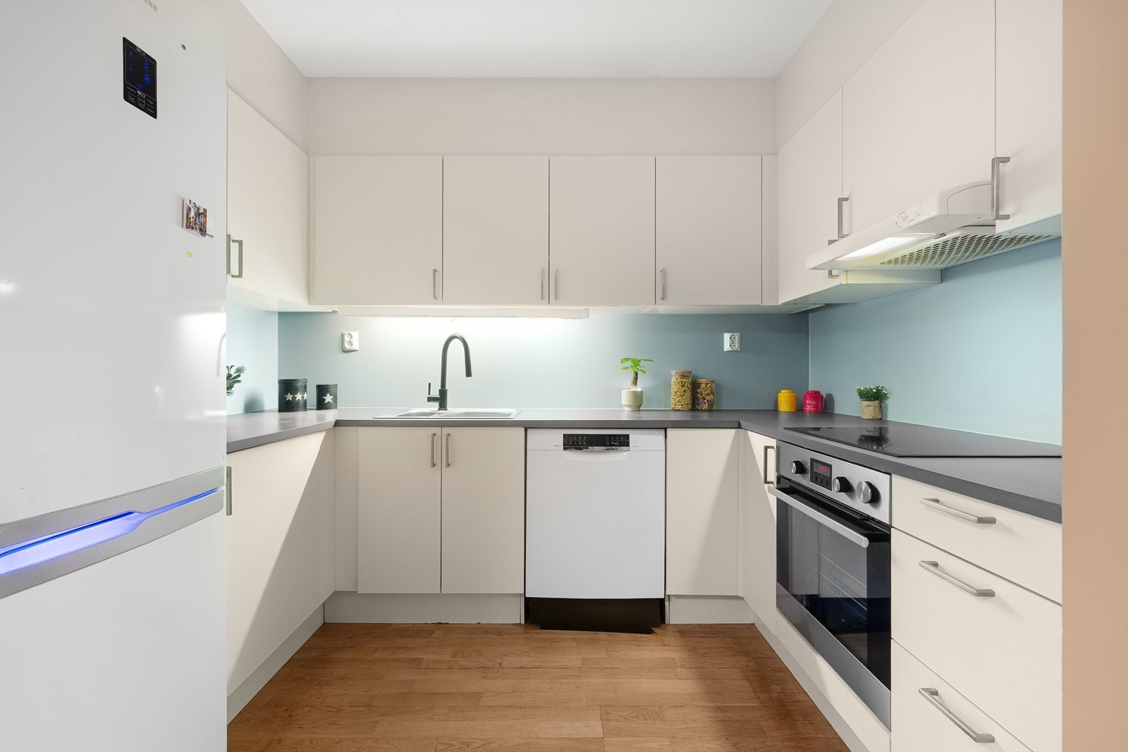 Kjøkkeninnredning med hvite glatte fronter og benkeplate i laminat. Galleribilde