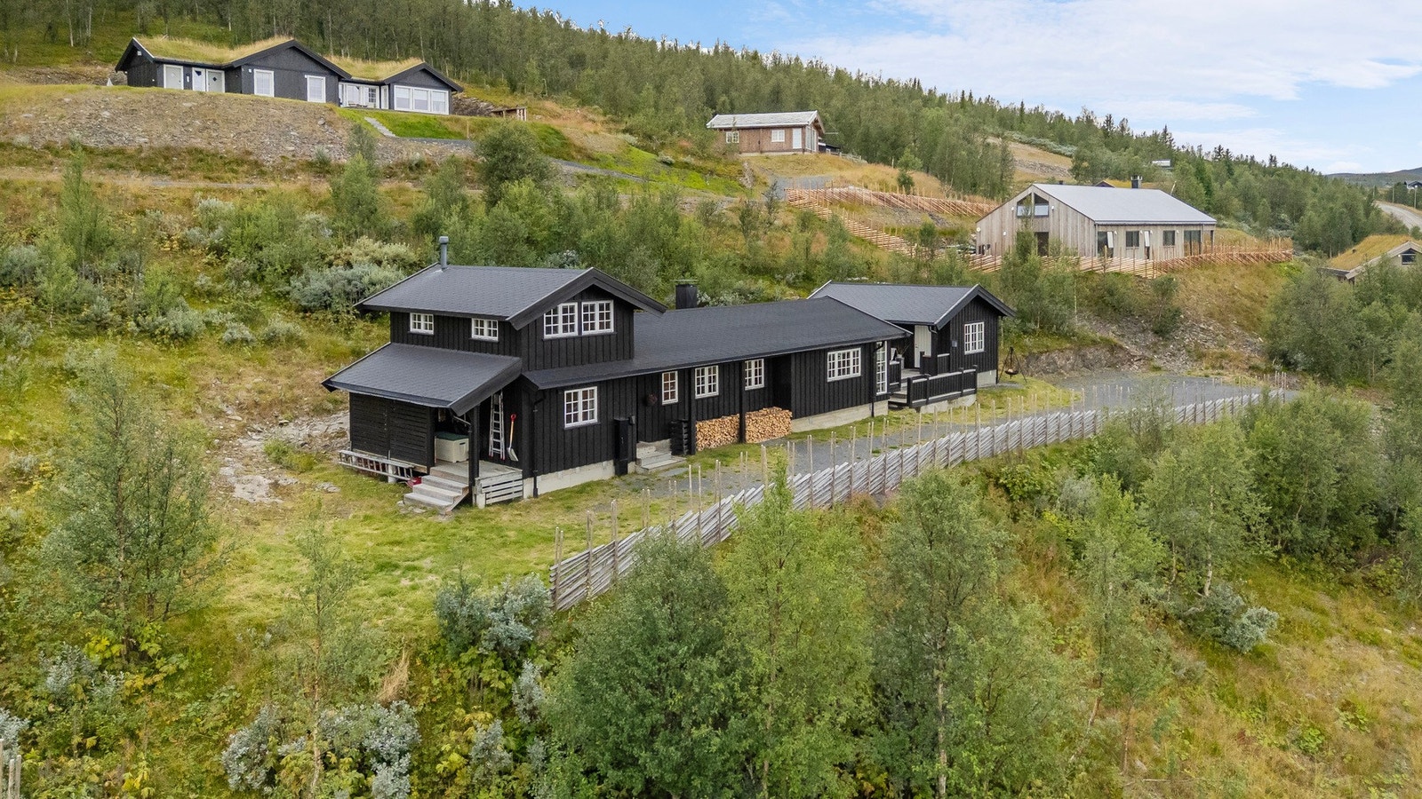 Hytta har også installert elbillader på hyttevegg samt praktisk overbygd langveggsbod som er velegnet for oppbevaring av ved Galleribilde