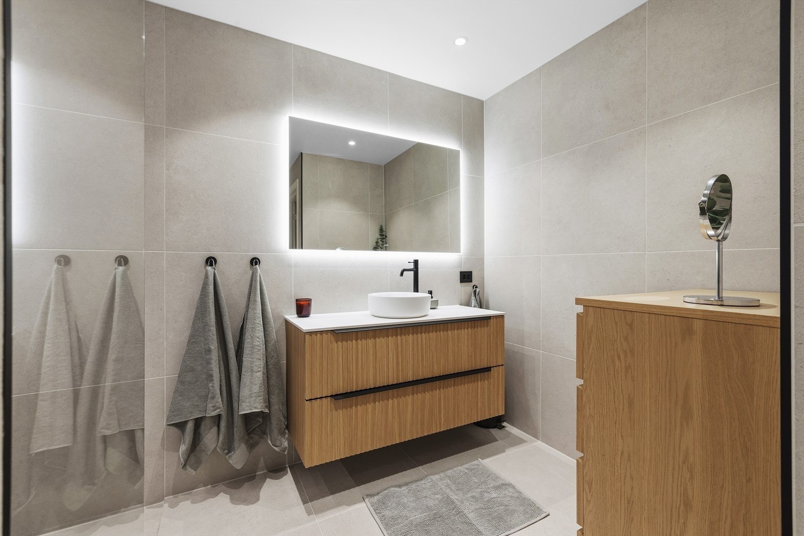 Lekker baderomsinnredning med skuffer og overliggende servant. Tilhørende speil med belysning Galleribilde