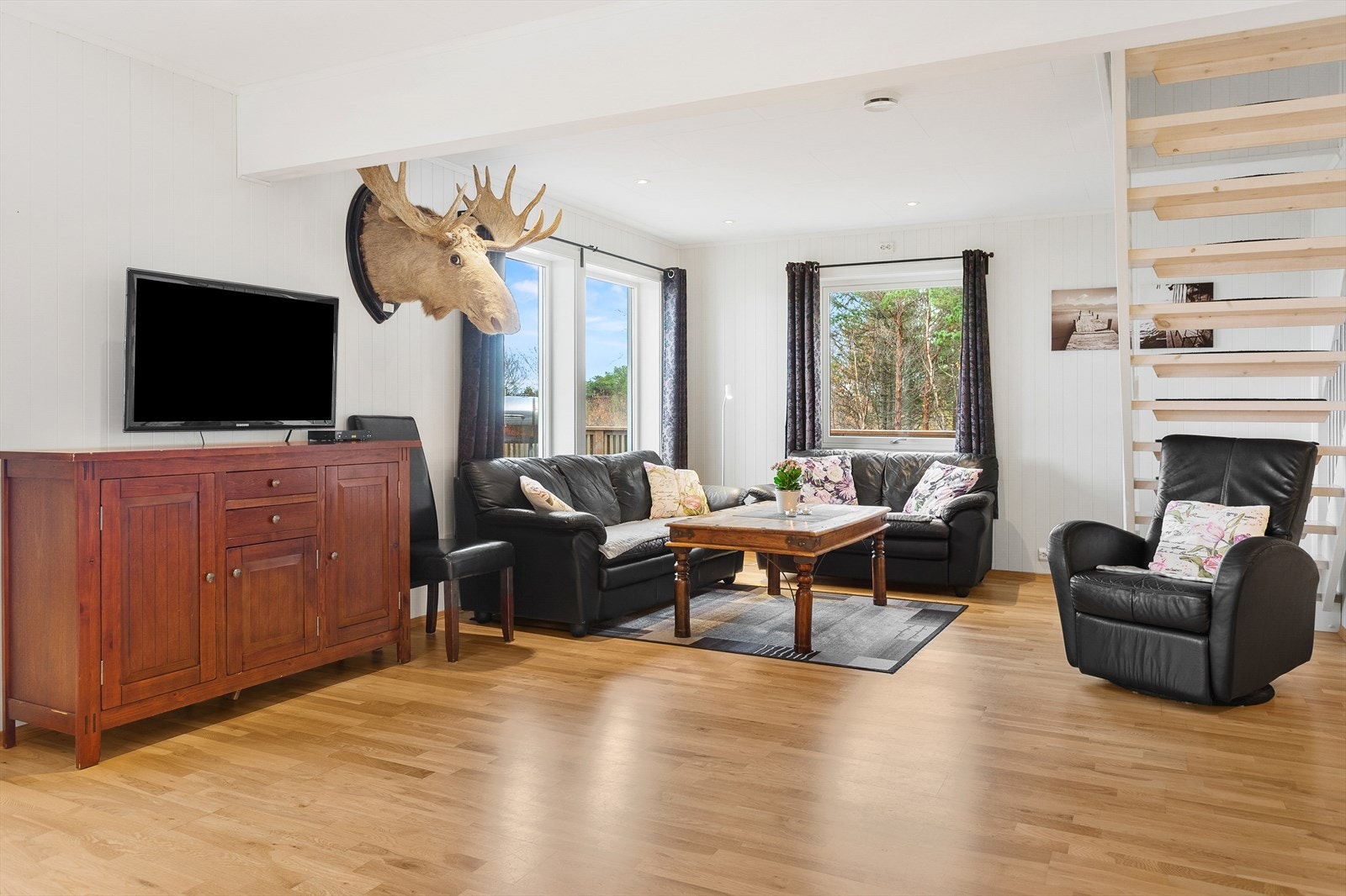 Sofagruppe plassert ved store vinduer gir utsyn mot uteområdet. Galleribilde