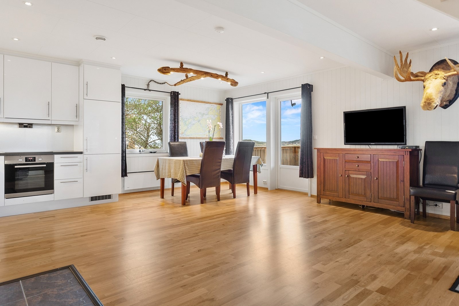 Åpen stue- og kjøkkenløsning med parkettgulv og store vindusflater gir lys og romfølelse. Galleribilde