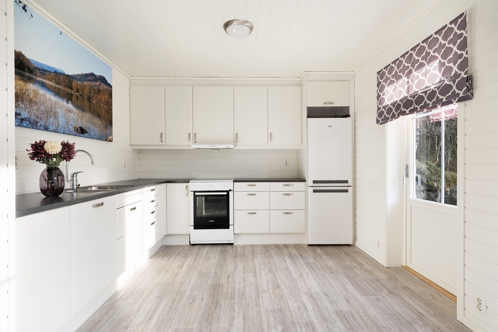 Kjøkkendelen har kvite glatte frontar og benkeplate av laminat. Galleribilde