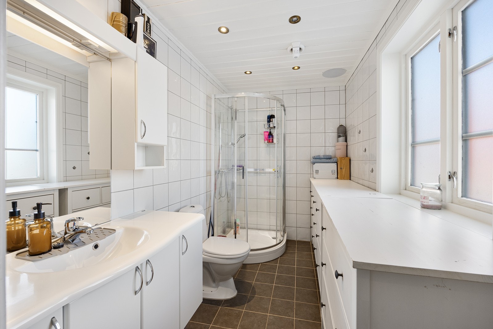 Pent flislagt bad med gulvvarme, servant i baderomsinnredning, toalett og dusjkabinett. Galleribilde