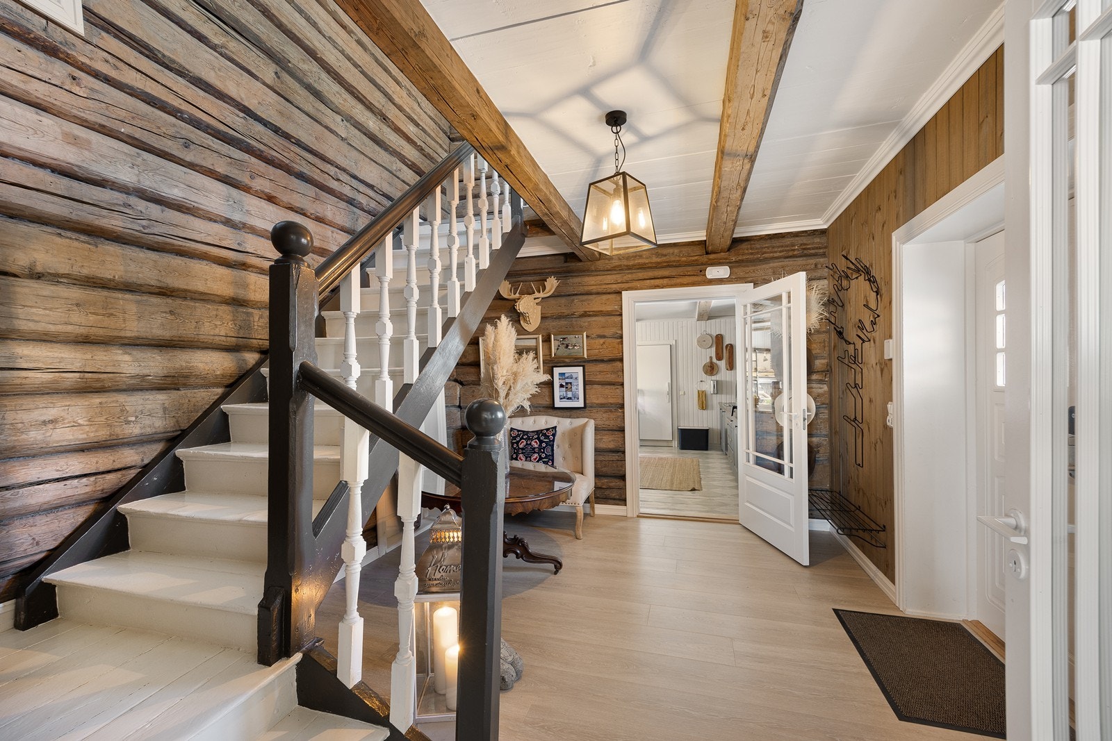 Hovedinngangen har tofløyet dør inn til en luftig hall med lune tømmervegger og rustikke takbjelker. Galleribilde