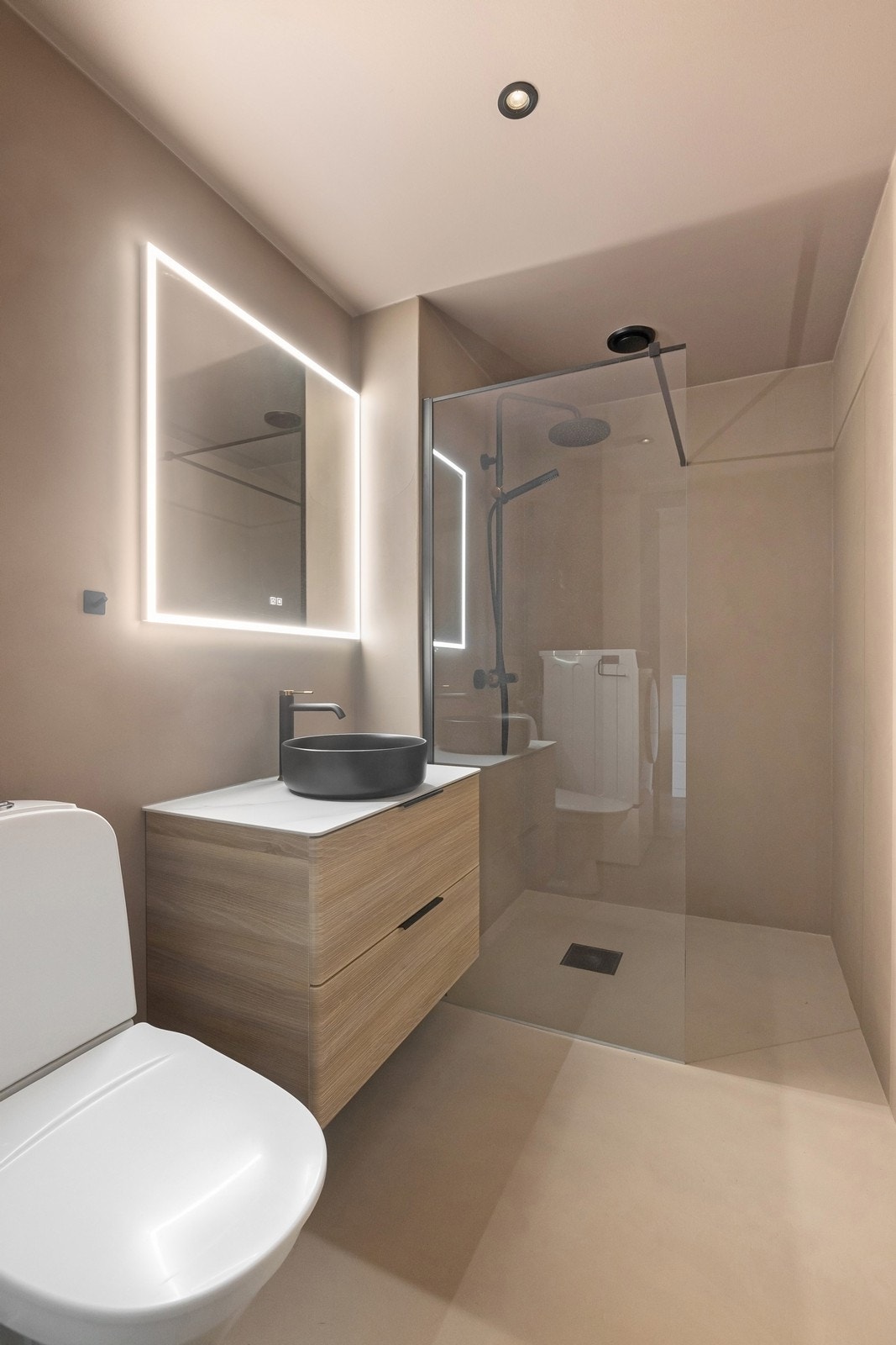 Badet er innredet med servant i baderomsinnrending, speil med integrert belysning, dusjhjørne med glassvegg og toalett. Galleribilde