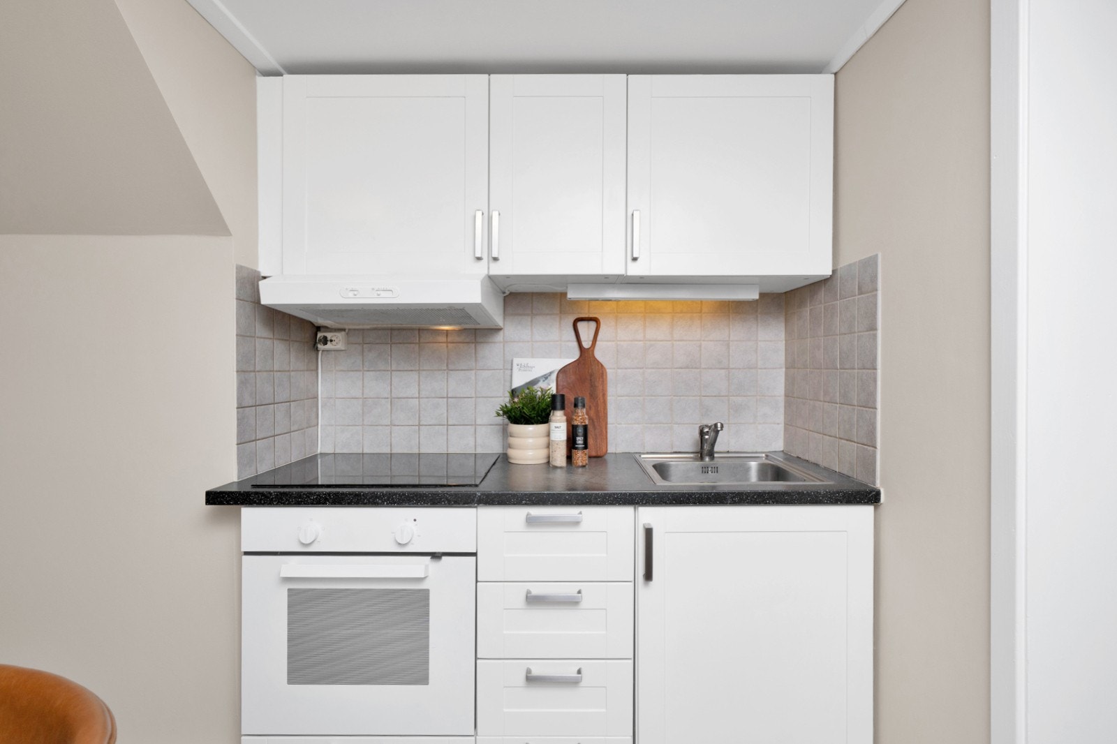 Videre består innredningen av platetopp, stekeovn og kjøkkenventilator med kullfilter. Det er montert fliser på vegg Galleribilde