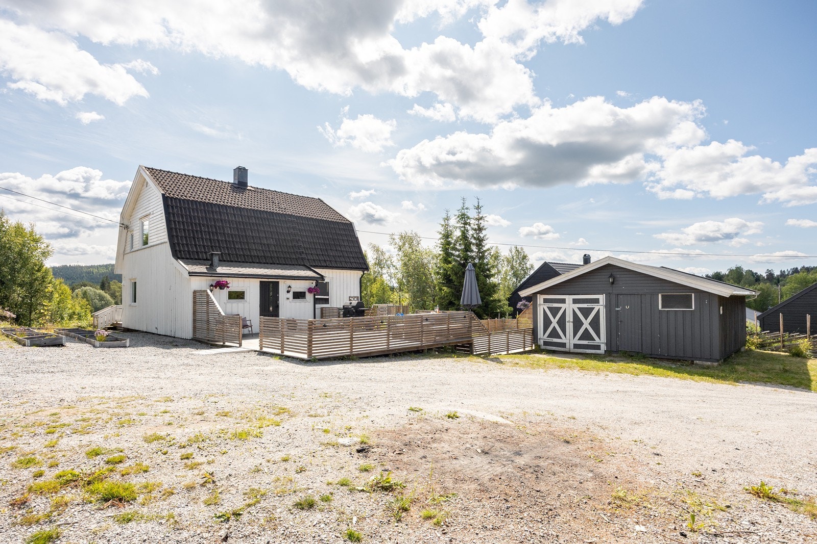 Gårdsplassen er gruset har god plass til flere biler. I tillegg er det to garasjer, hvorav den ene har to hestebokser. Galleribilde