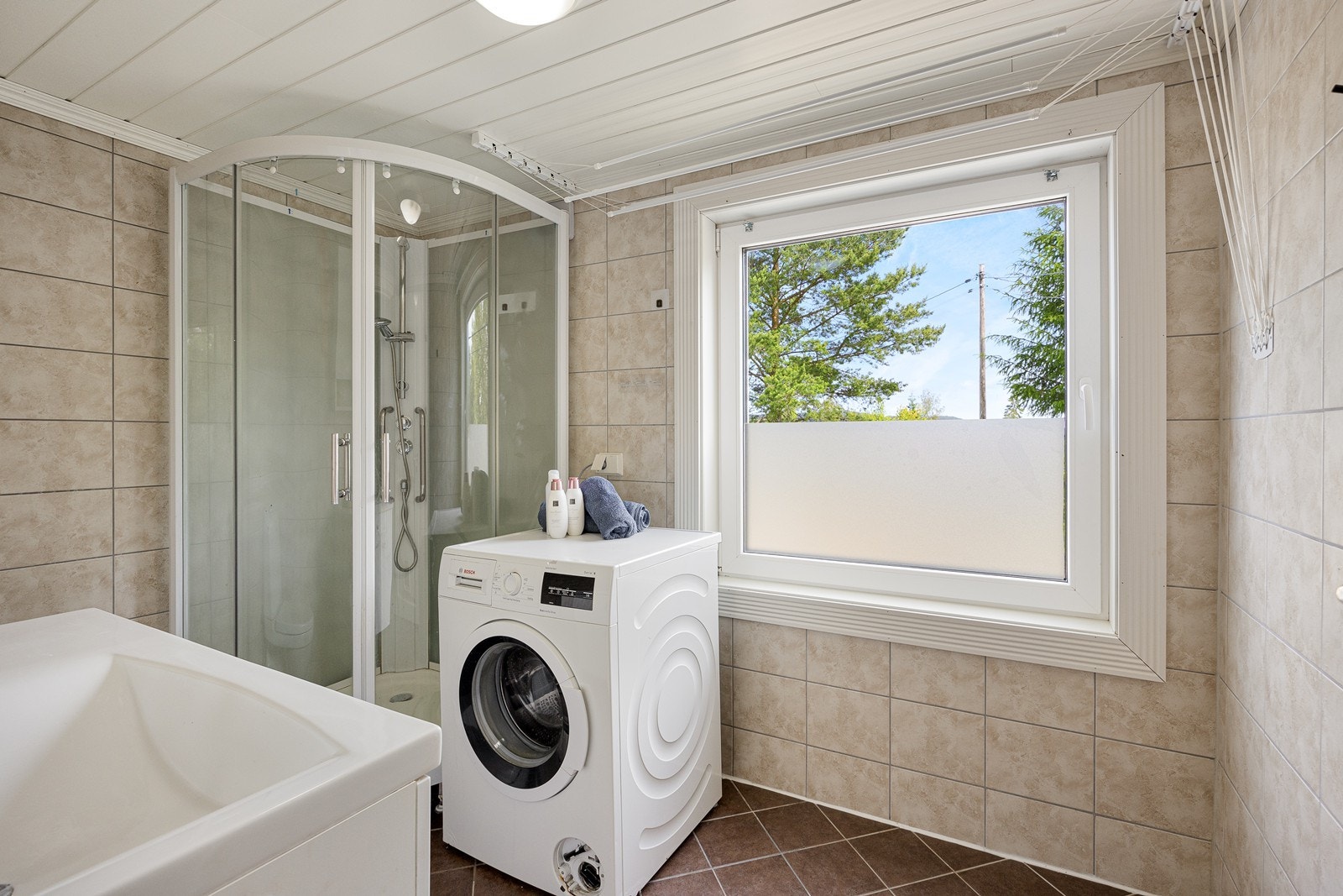 Innredningen har hvite fronter og heldekkende servant på en skapseksjon, et veggskap og et speil med belysning. Badet har toalett, dusjkabinett og opplegg for vaskemaskin. Galleribilde