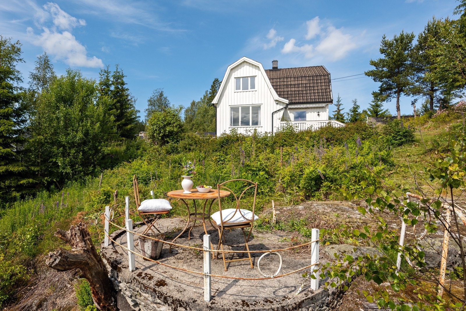 Tomten er pent opparbeidet med store plenarealer, prydbusker og fjell i dagen. Galleribilde
