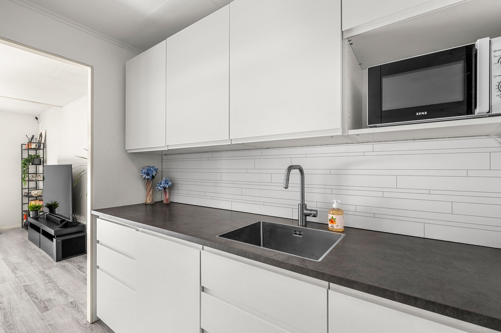 Kjøkkenet har integrerte hvitevarer som platetopp, komfyr og oppvaskmaskin. Innredningen har slette fronter og benkeplate i laminat. Galleribilde