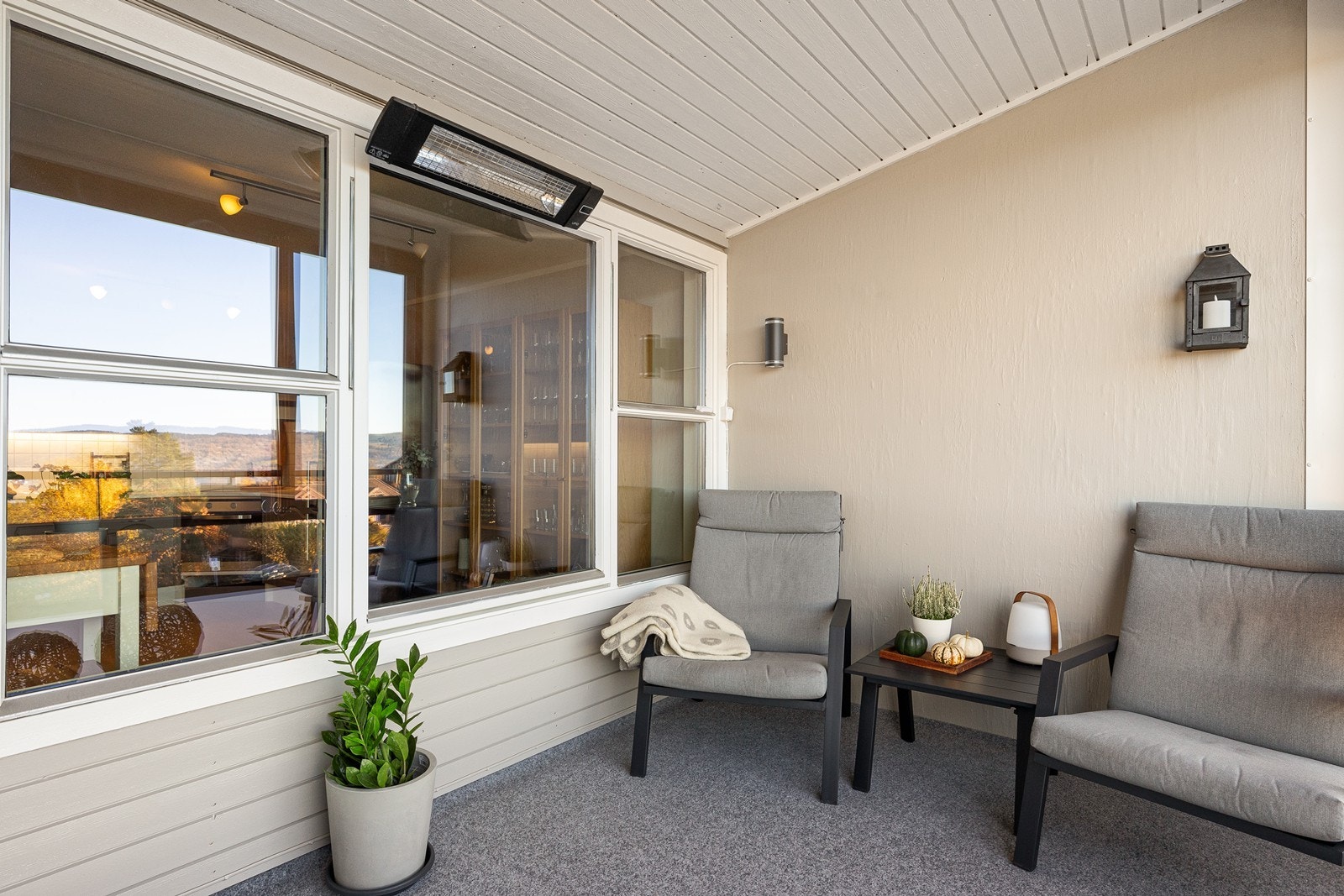 Overbygget og innglasset balkong med stråleovn og teppe på gulv. Galleribilde