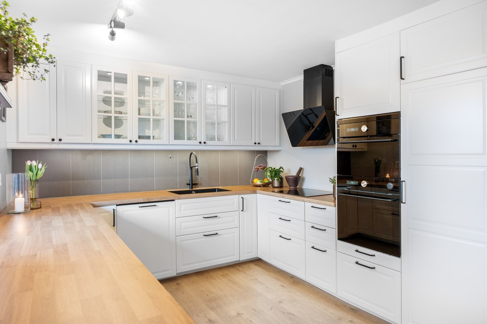 De sorte detaljene på håndtak, armatur, kum og hvitevarer står i moderne kontrast til de hvite frontene. Her får du både stekeovn og kombiovn i praktisk høyde. Galleribilde