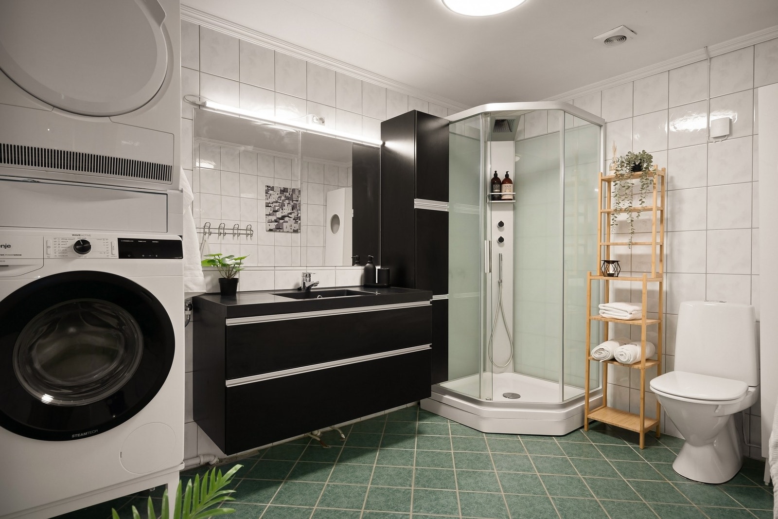 Flislagt bad med servant, høyskap, dusjkabinett, toalett og opplegg for vaskemaskin. Galleribilde