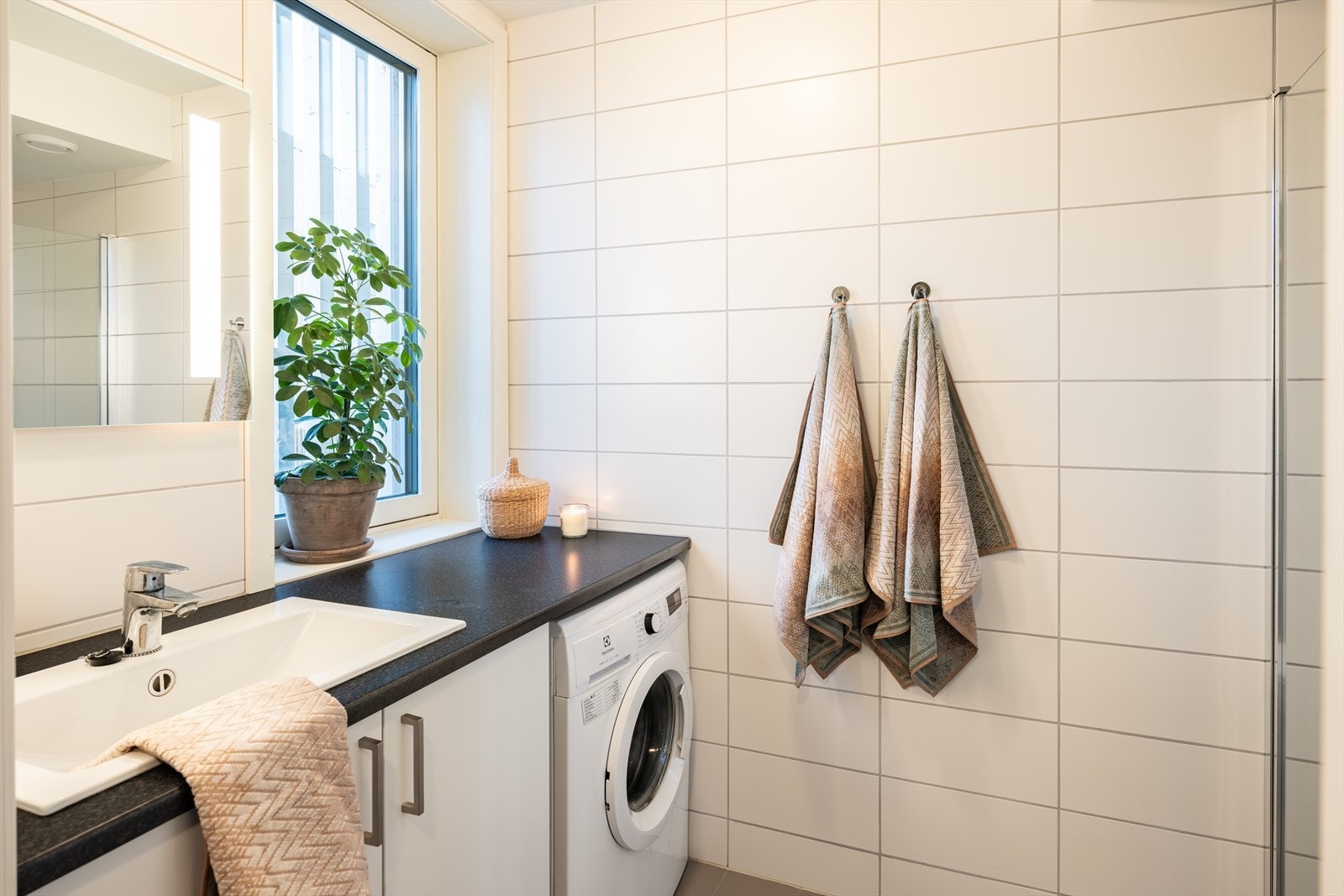 Flislagt baderom med svært god utforming. Her får man en romslige benkeplate med god plass, samt belysning innebygd i speilet. Baderomsinnredning er fra Sigdal. Galleribilde