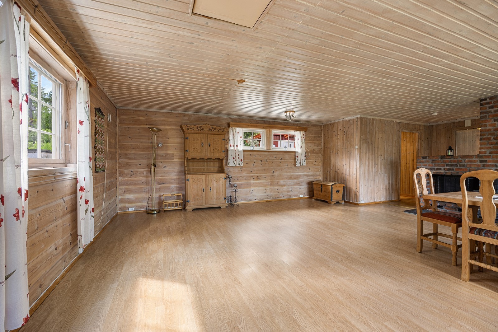 Laminat på gulvet kombineres med trepanel på veggene, og utformingen gjør stuen enkel å møblere med flere sittegrupper. Galleribilde