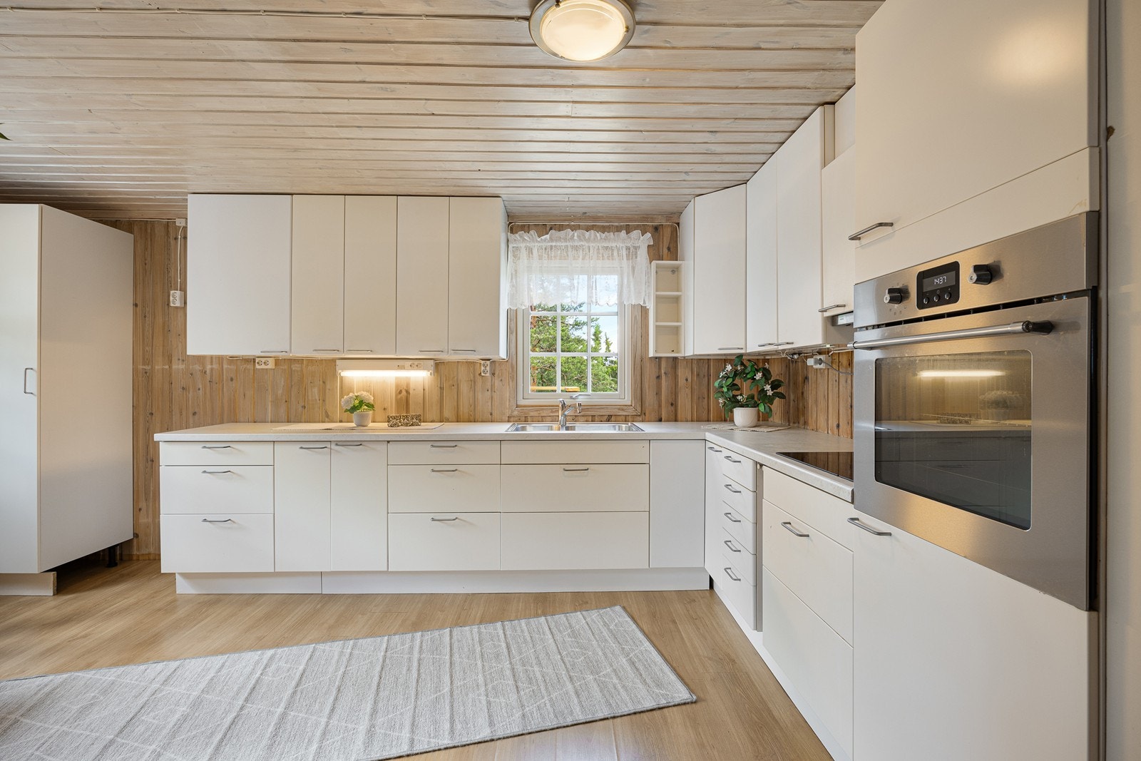 Belysning er montert over benken, og over kokesonen har kjøkkenet hvite fliser og en ventilator med avtrekk ut. Galleribilde