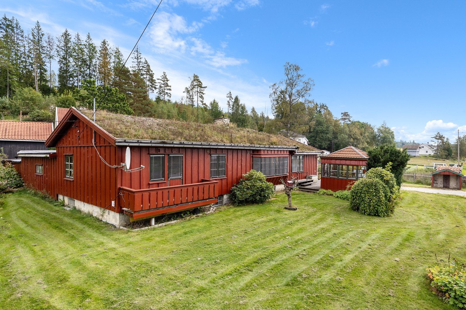 Boligen har torvtak og rødmalt villmarkspanel, og utenfor husveggen mot sørvest, er det både veranda og terrasse. Galleribilde