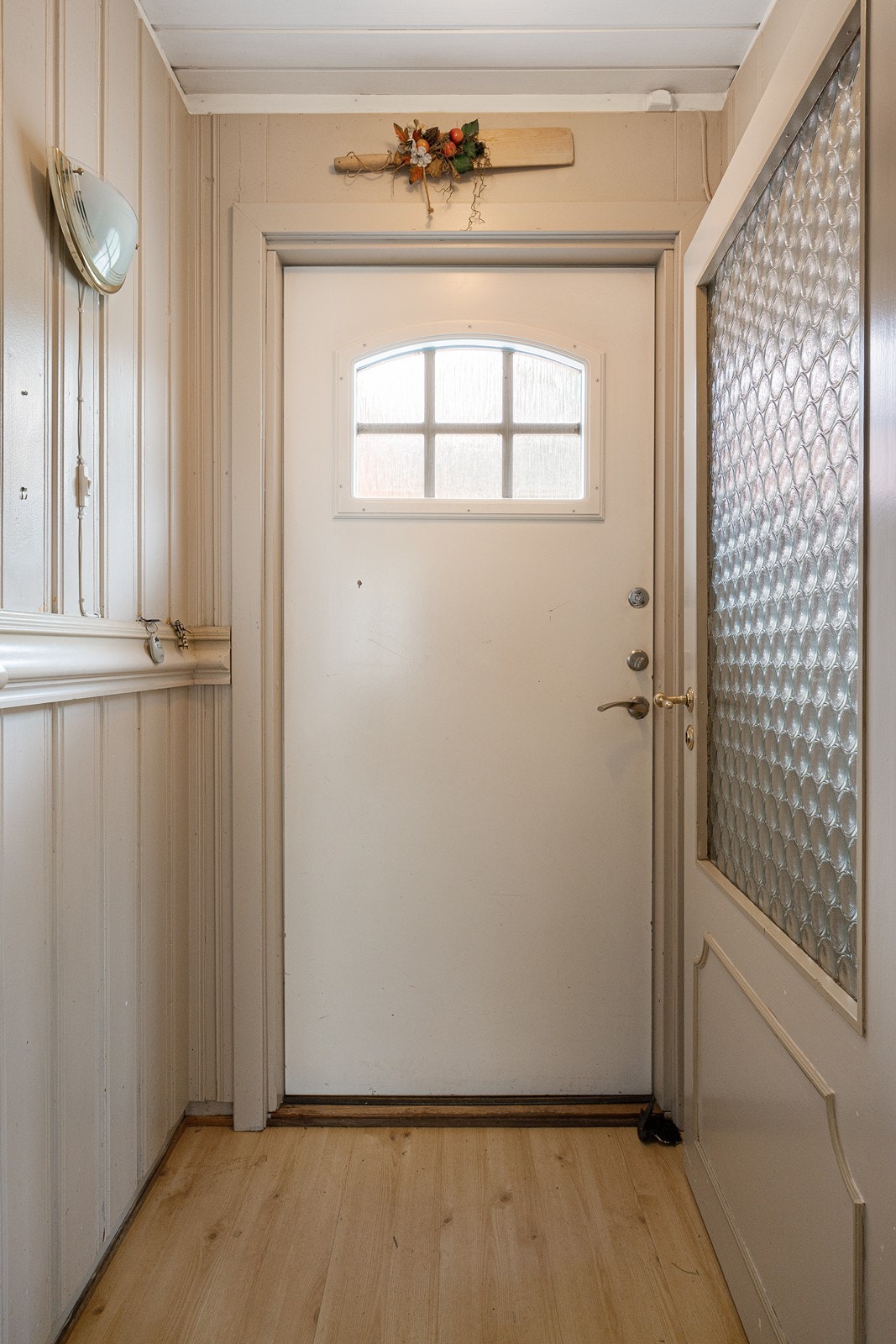 Innenfor venter et vindfang med laminatgulv og beigemalte panelvegger. Galleribilde