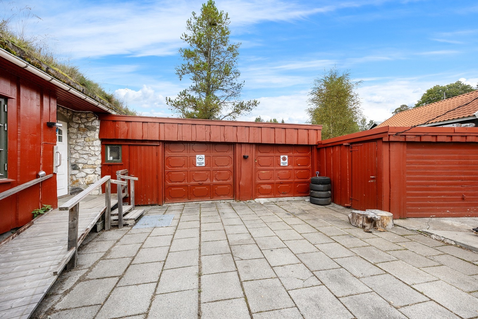 Fra gårdsplassen er det trapp og rullestolrampe opp til et inntrukket inngangsparti. Inngangspartiet har flislagt tram, steinsatte vegger og en hvit dør med glassfelt. Galleribilde